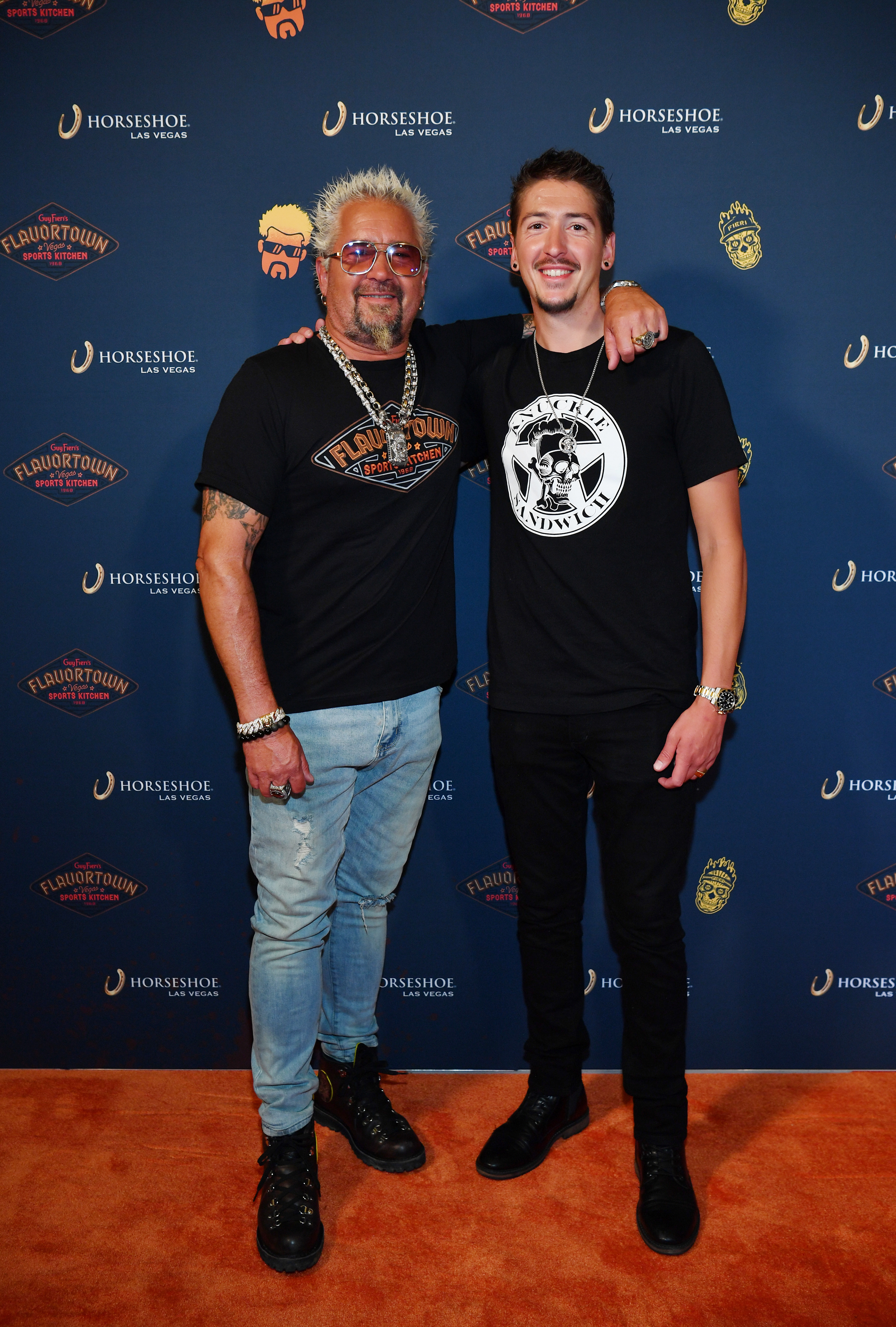 Guy and Hunter Fieri pose on the orange carpet at the grand opening of the former's Flavortown Sports Kitchen on July 7, 2023, in Las Vegas, Nevada | Source: Getty Images