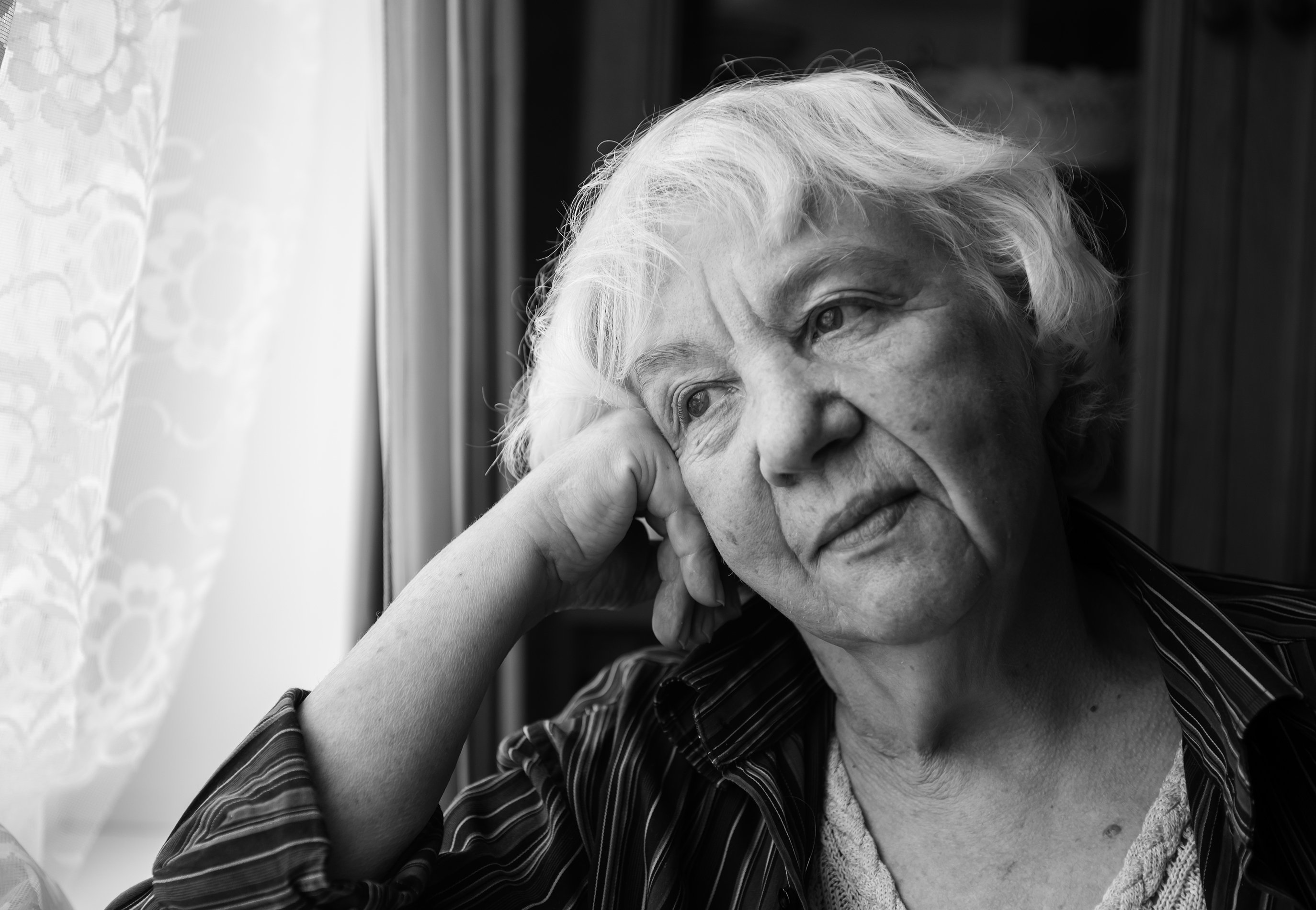 Mujer mayor mira al horizonte a través de la ventana. | Foto: Shutterstock