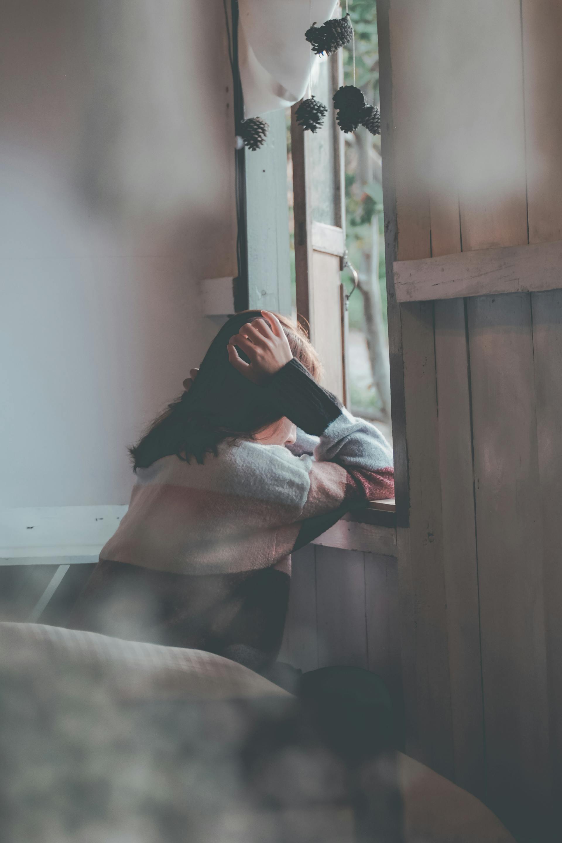 A woman leaning on a window sill and looking outside | Source: Pexels