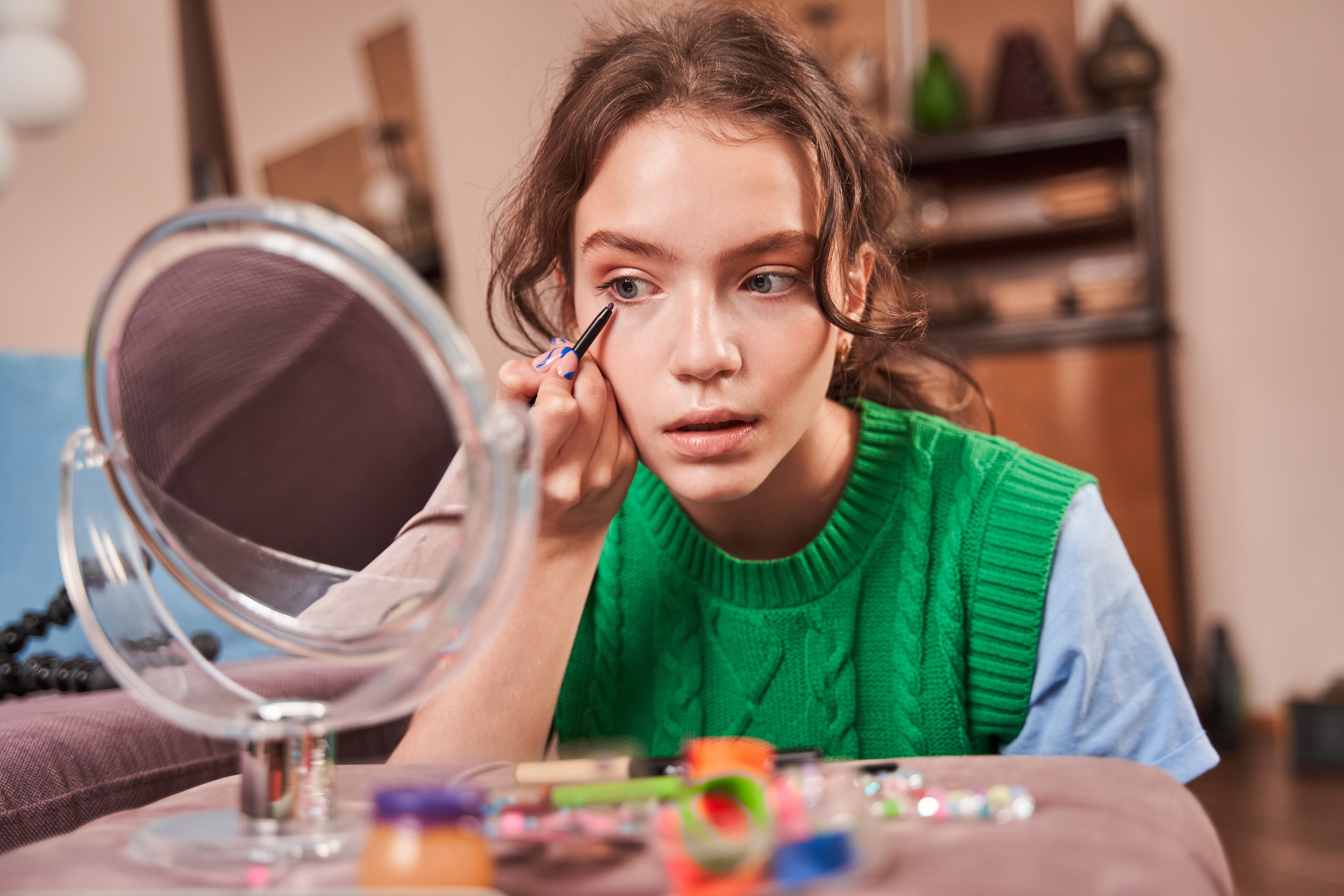 A teenage girl applies makeup while looking in the mirror | Source: Shutterstock