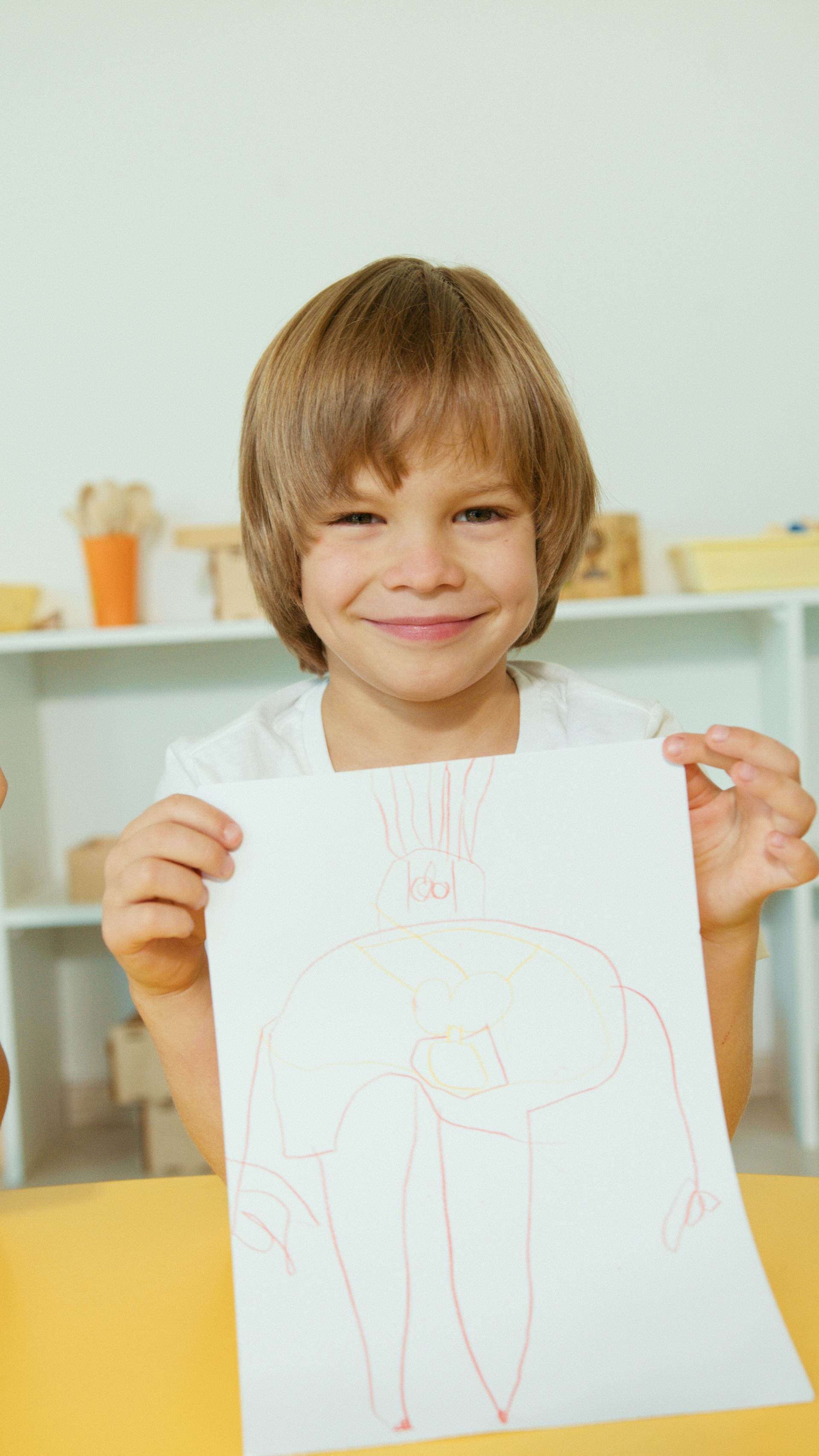 A smiling little boy showing his artwork | Source: Pexels
