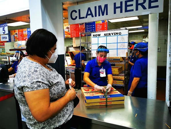 Une femme portant un masque facial achète une pizza dans un supermarché. |Photo : Getty Images Une femme portant un masque facial achète une pizza dans un supermarché. |Photo : Getty Images