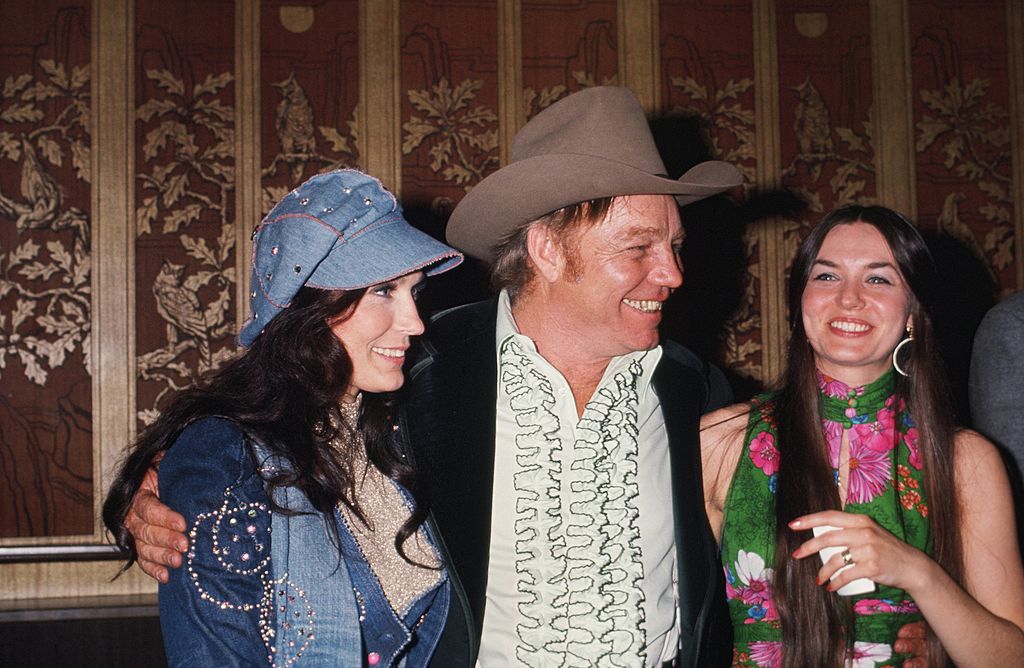 Country singers and sisters Loretta Lynn [Left] and Crystal Gayle flank Loretta's husband Mooney Lynn at a soiree in circa 1976. | Source: Getty Images