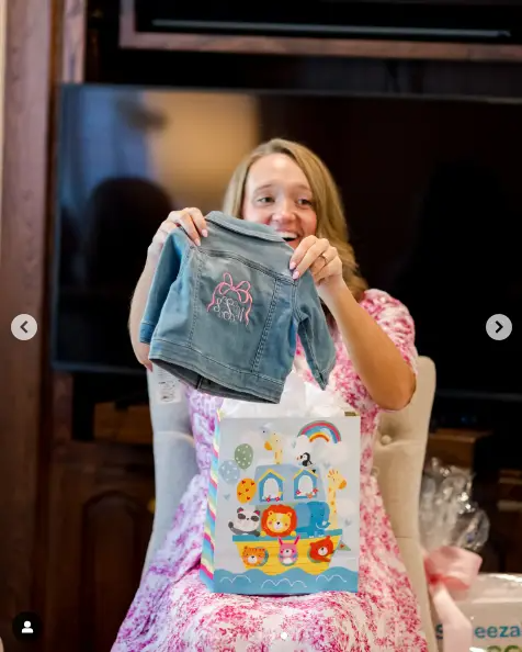 Alex Drummond lit up with excitement as she held up a tiny denim jacket for her baby girl, one of the many thoughtful gifts she received at her baby shower. The moment captured the joy and anticipation surrounding her journey into motherhood. | Source: Instagram/thepioneerwoman