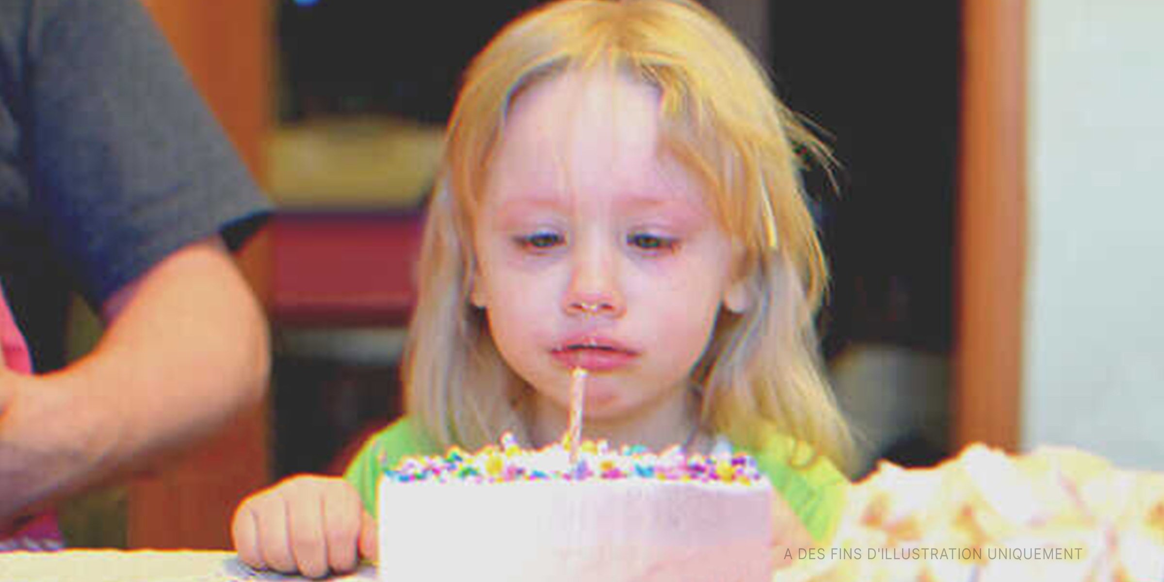 Une petite fille devant un gâteau d'anniversaire | Shutterstock