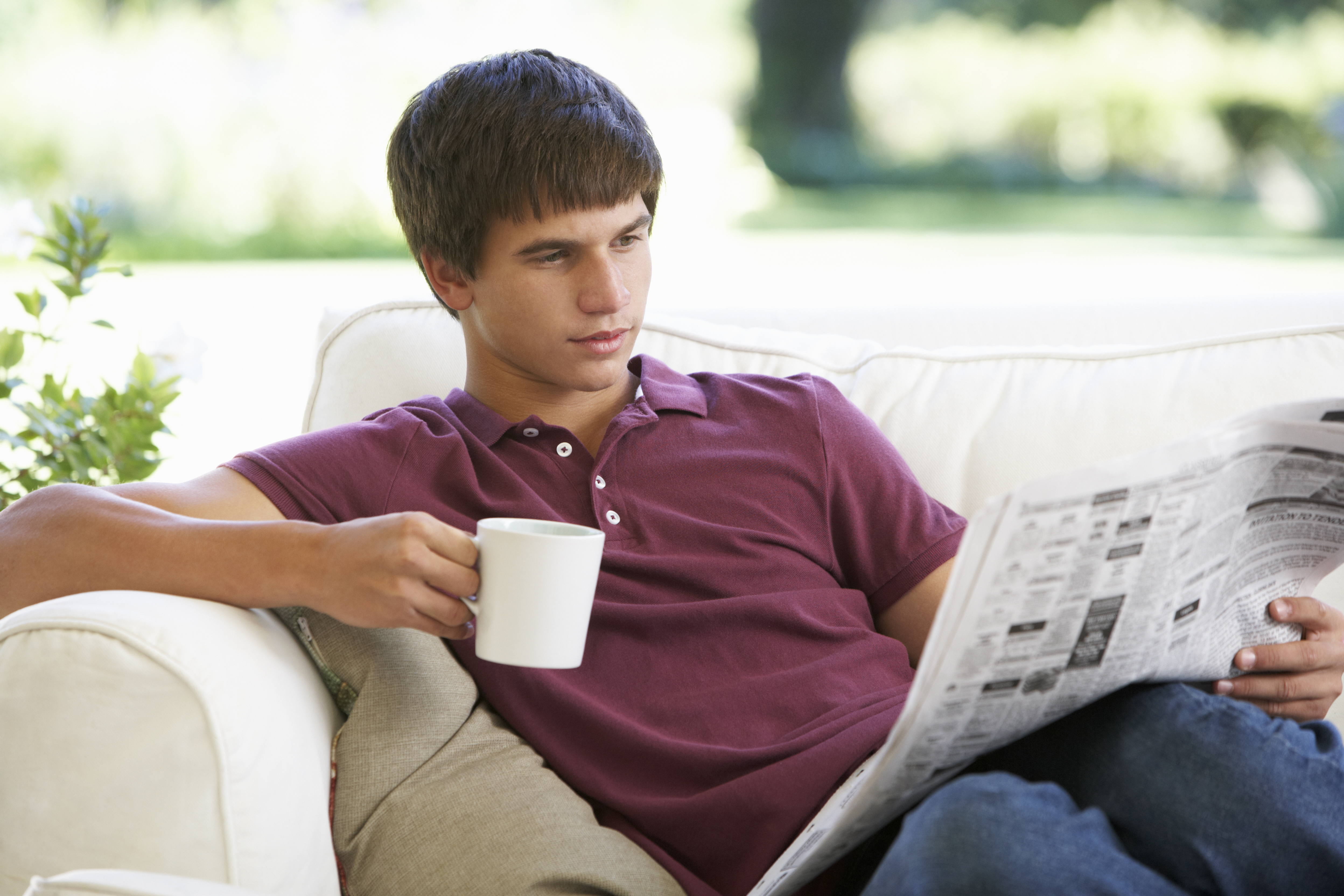 A teenage boy reads a newspaper | Source: Shutterstock