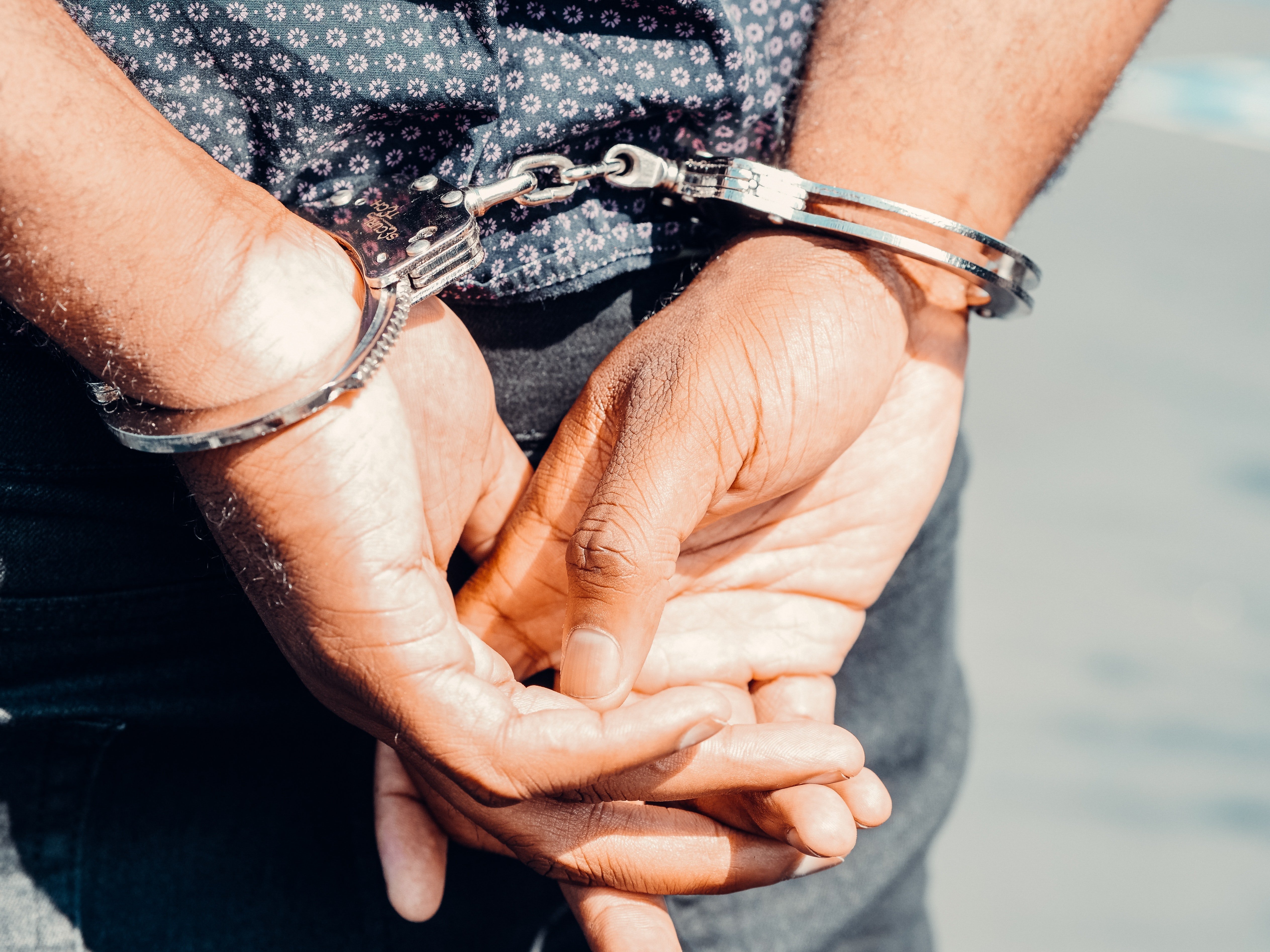 Pictured - A photo of a man in handcuffs wearing jeans and a floral shirt | Source: Pexels 