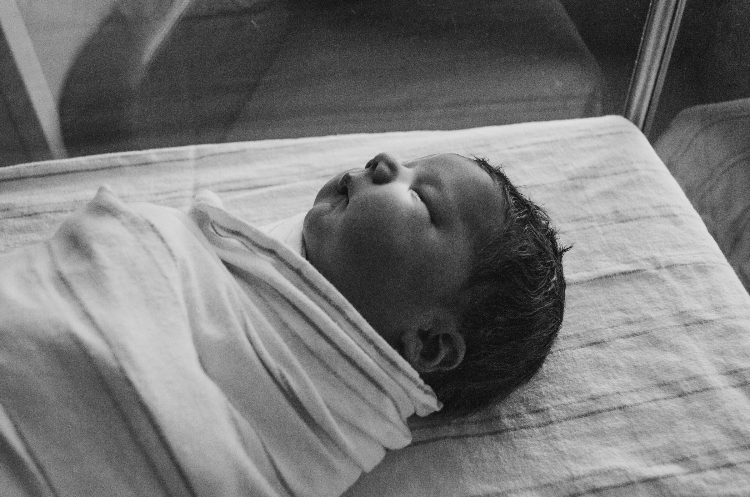 A grayscale photo of a newborn baby wrapped in a cloth | Source: Unsplash