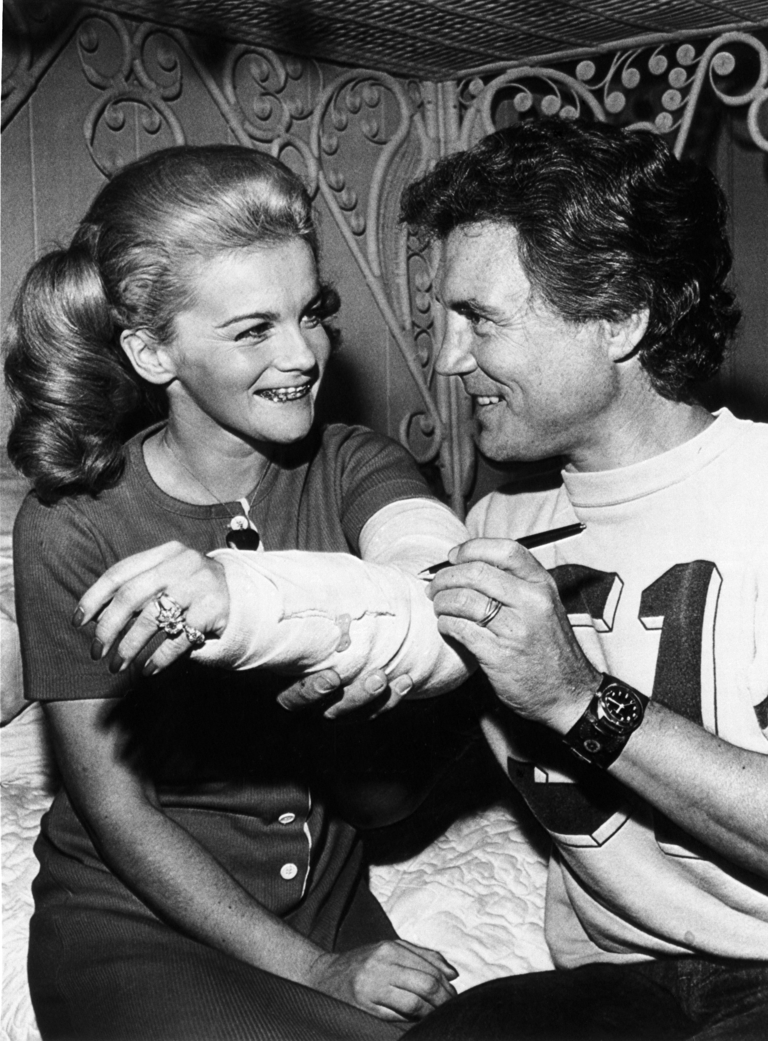 Ann-Margret after suffering a near fatal accident in a fall from a platform during her act in Lake Tahoe, has the cast on her broken left arm signed by her spouse, Roger Smith. / Source: Getty Images