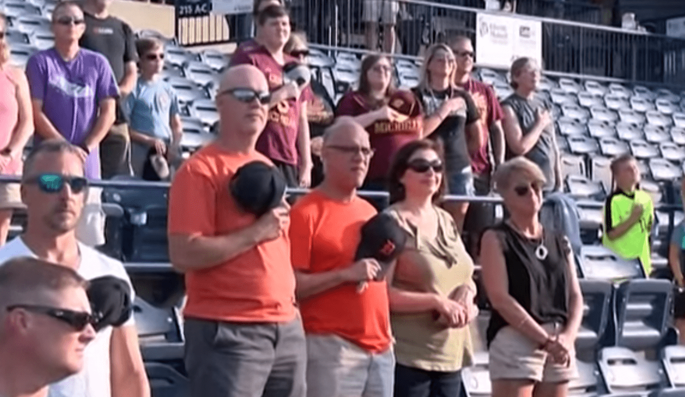 Spectators at a baseball game watch in awe as an elderly veteran sings the national anthem | Photo: Facebook/wmwcaps