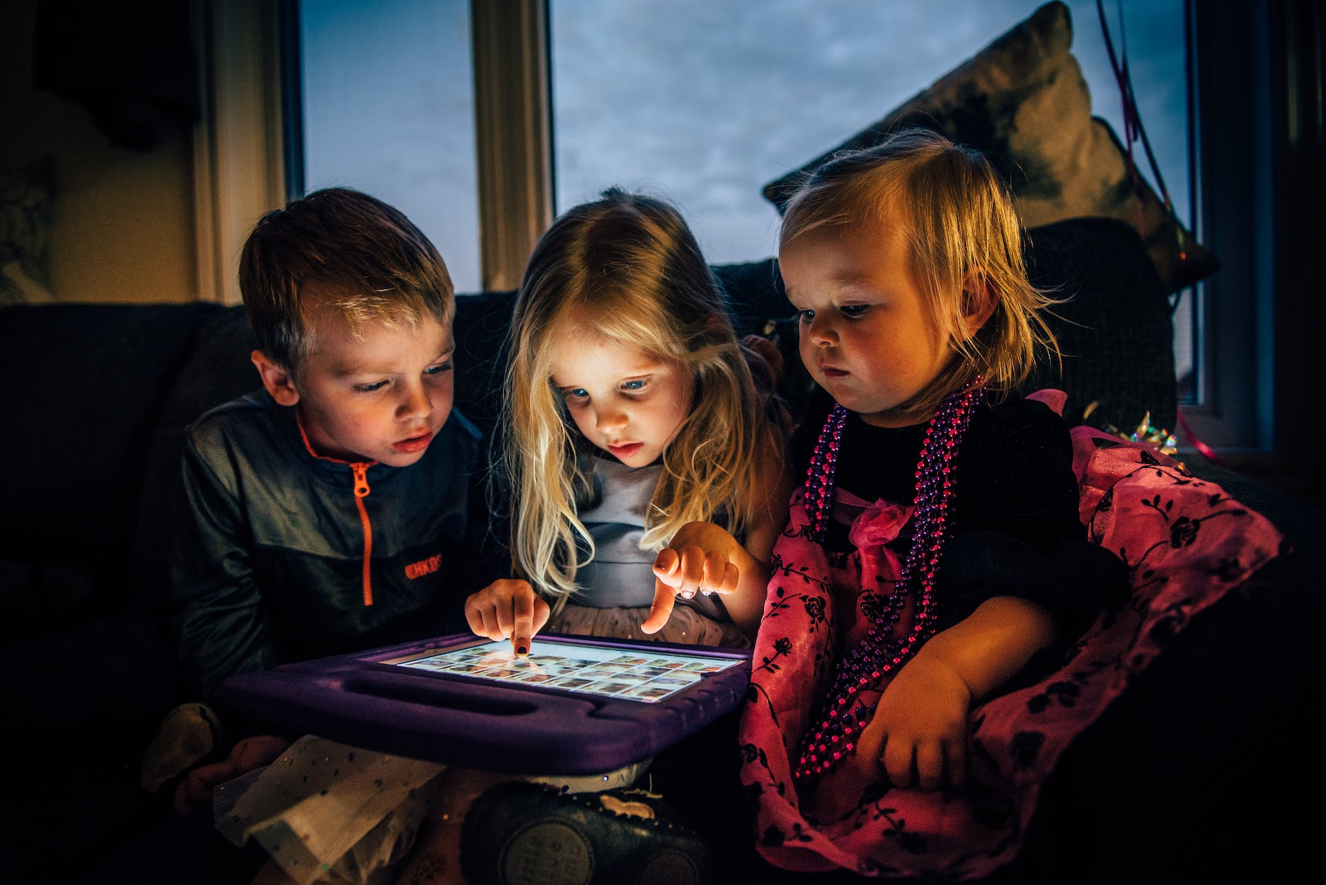 Three children looking at a tablet | Source: Pexels