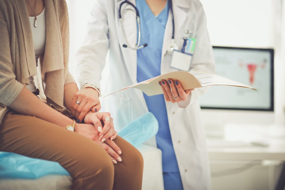 Ein Arzt und ein Patient diskutieren etwas, während sie bei einer Kontrolluntersuchung am Tisch sitzen. | Quelle: Shutterstock