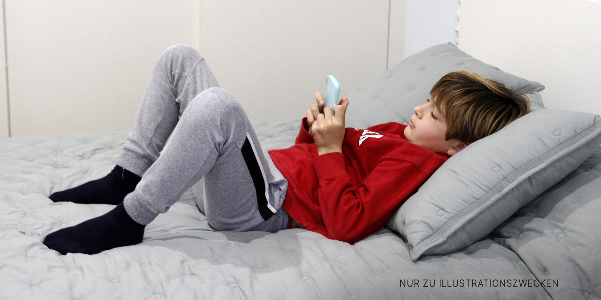 Ein Junge benutzt sein Handy auf dem Sofa | Quelle: Getty Images