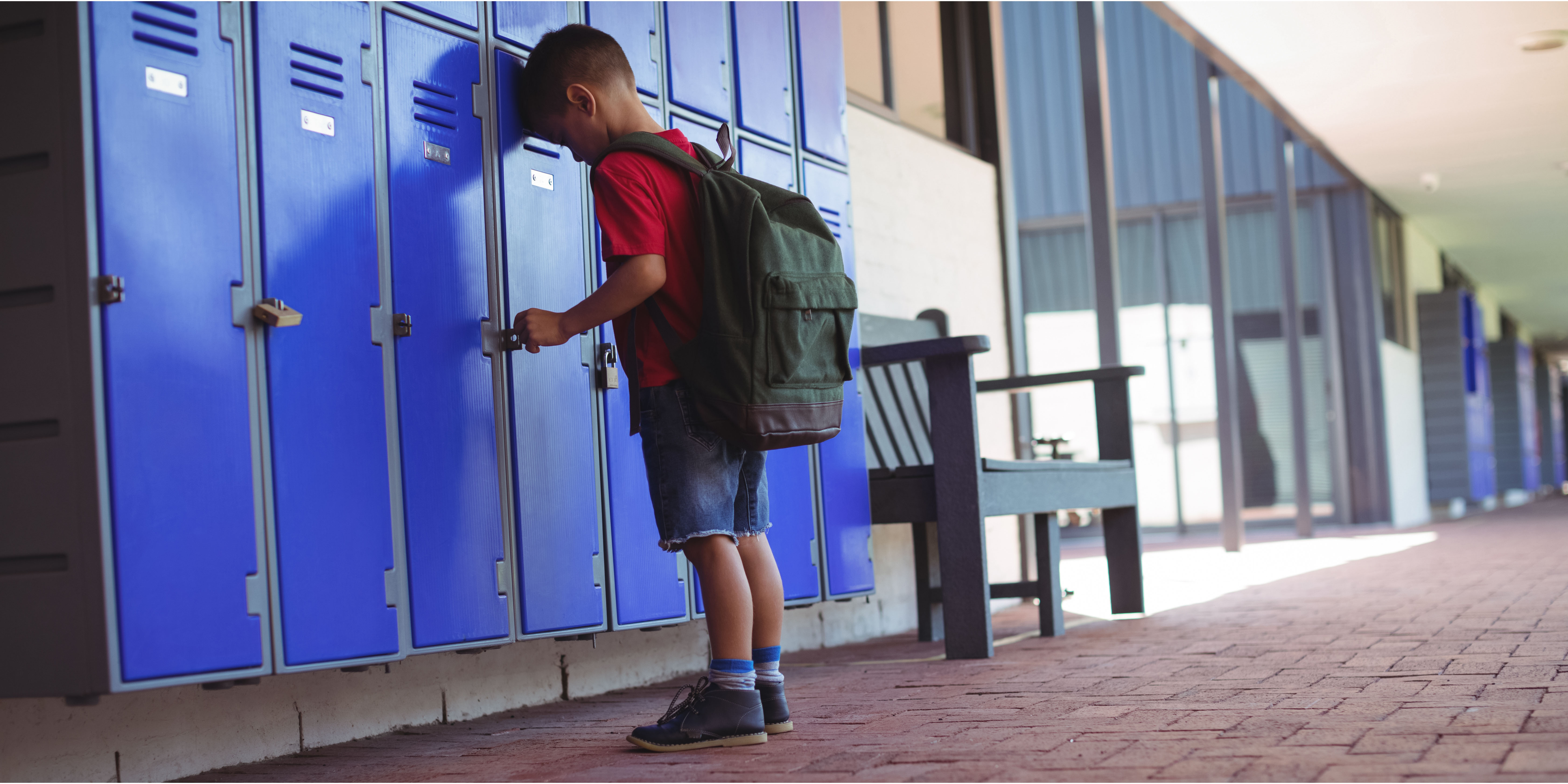 Sad boy leaned his head against the school locker | Source: Shutterstock