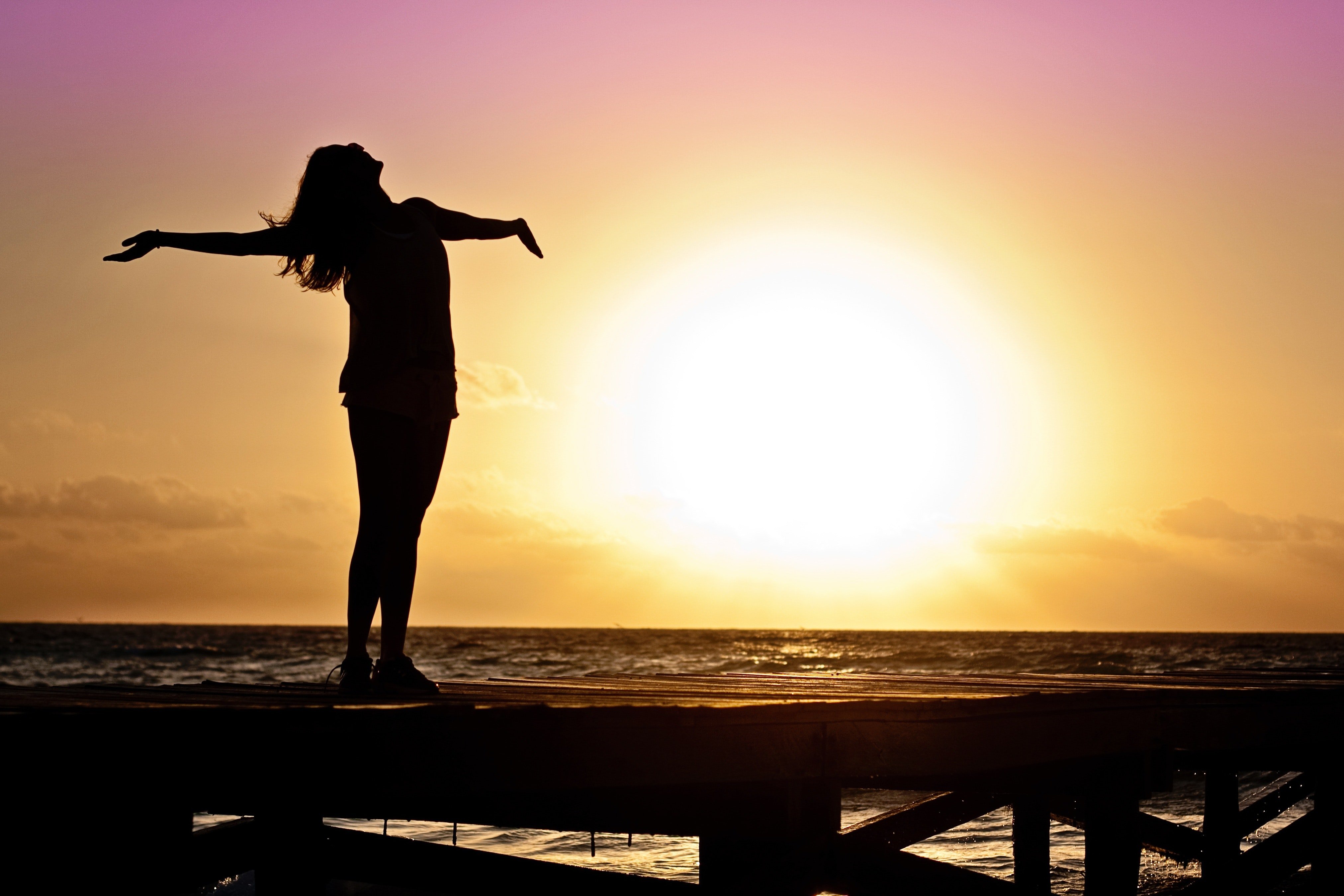 DA woman standing with her chest facing the sky while on the beach at sunset | Source: Pexels