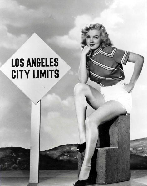 Marilyn Monroe poses in front of a signpost reading "Los Angeles City Limits" wearing t-shirt and shorts, circa 1950s. | Photo: Getty Images