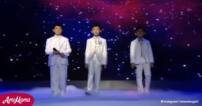 3 boys prepare to sing, 'You Raise Me Up'. After music begins to play, the crowd is enchanted
