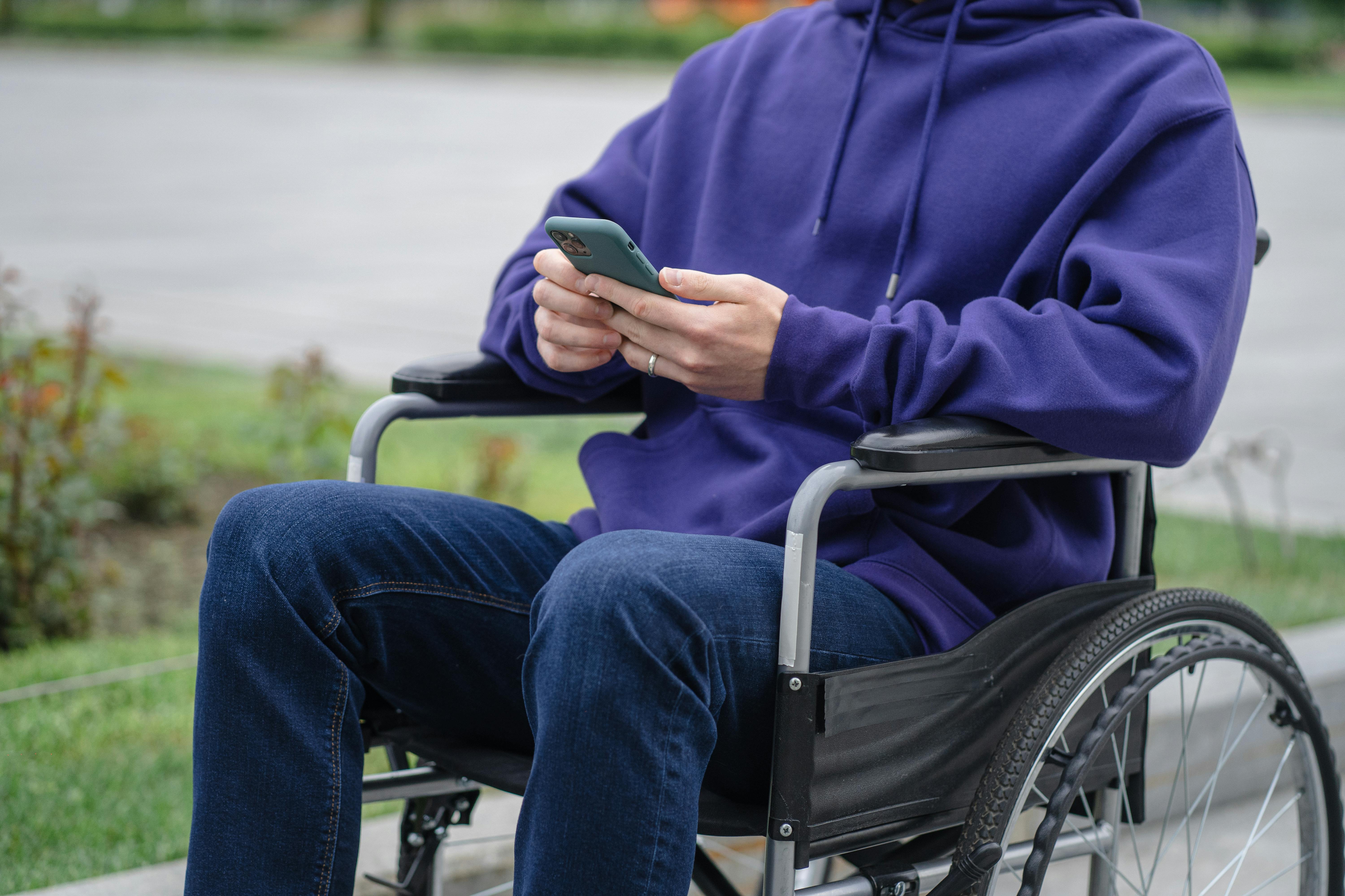 A man on his phone while sitting on a wheelchair | Source: Pexels