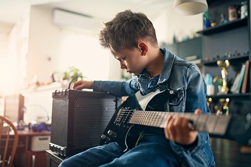 Photo of a little boy playing electric guitar in the living room | Photo: Getty Images