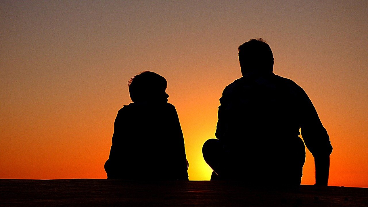 A picture of a father and his son sitting and talking while watching the sunset. | Photo: Pixabay
