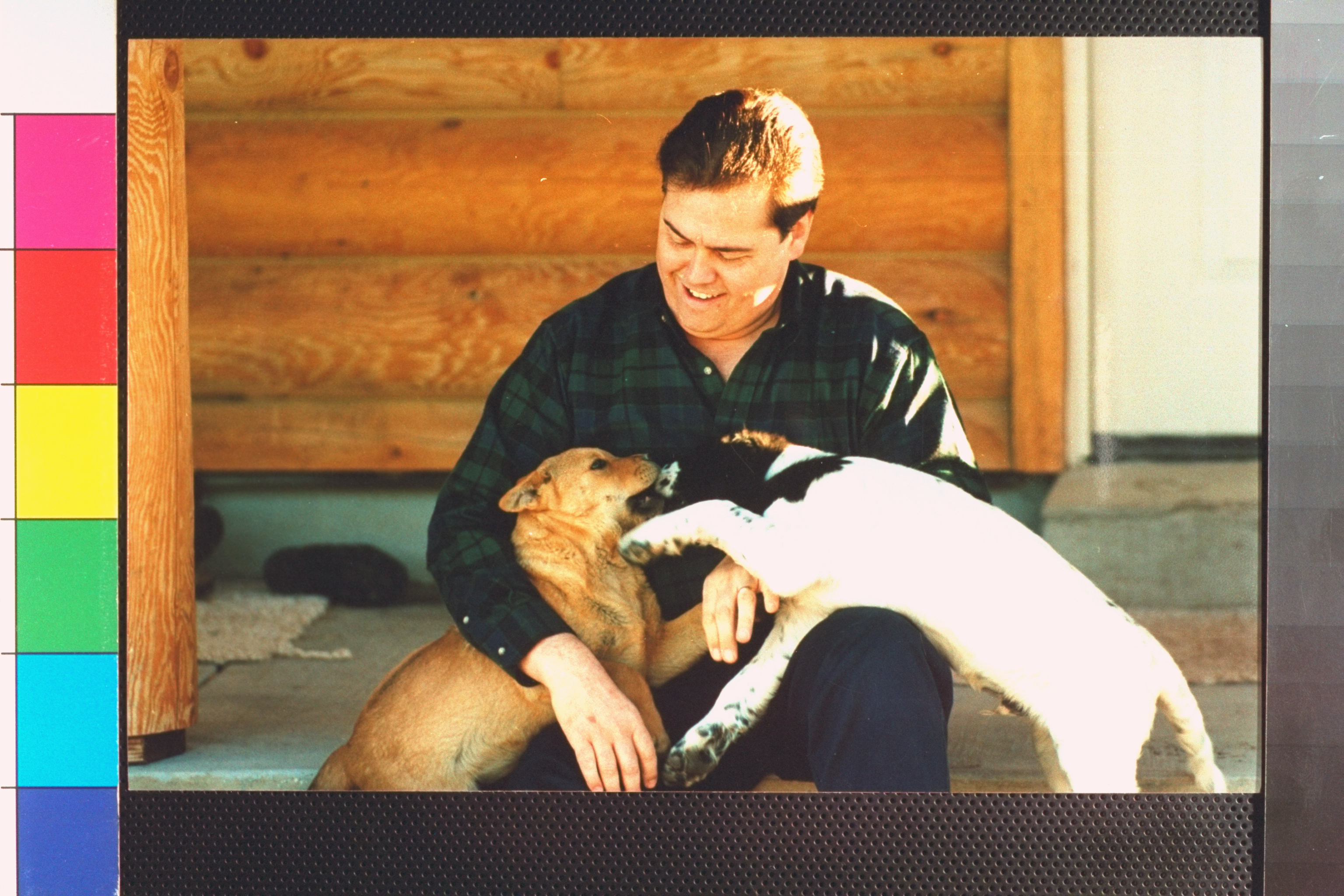 Alan Osmond playing with his 2 pet dogs while sitting on porch in front of his ranch in 1995 | Source: Getty Images