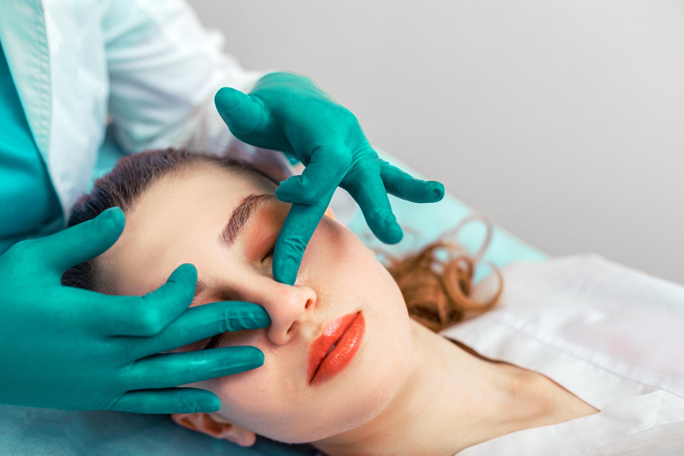 The surgeon hands touches the patient's nose | Source: Getty images