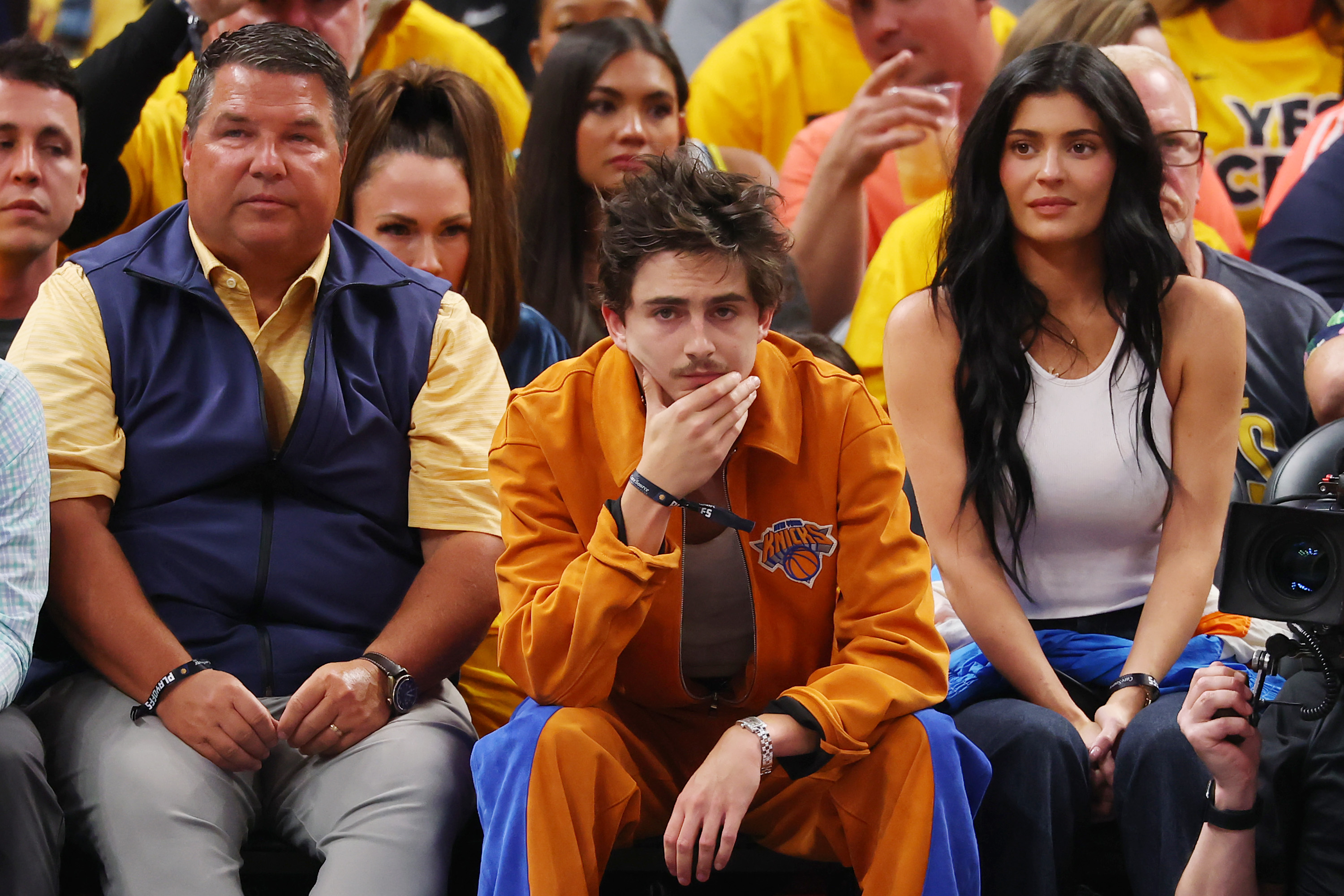 Timothée Chalamet, in an orange outfit with his curly hair loose and messy, attended Game Six of the Eastern Conference Finals with Kylie Jenner on May 31, 2025, at Gainbridge Fieldhouse in Indianapolis, Indiana.