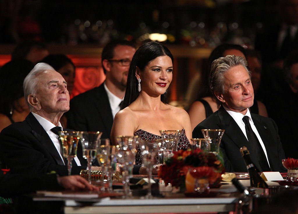 Catherine Zeta-Jones flanked by her late father in law, Kirk Douglas (L) and husband Michael Douglas (R) at the AFI Lifetime Achievement Award on June 11, 2009 in California. | Photo: Getty Images.  