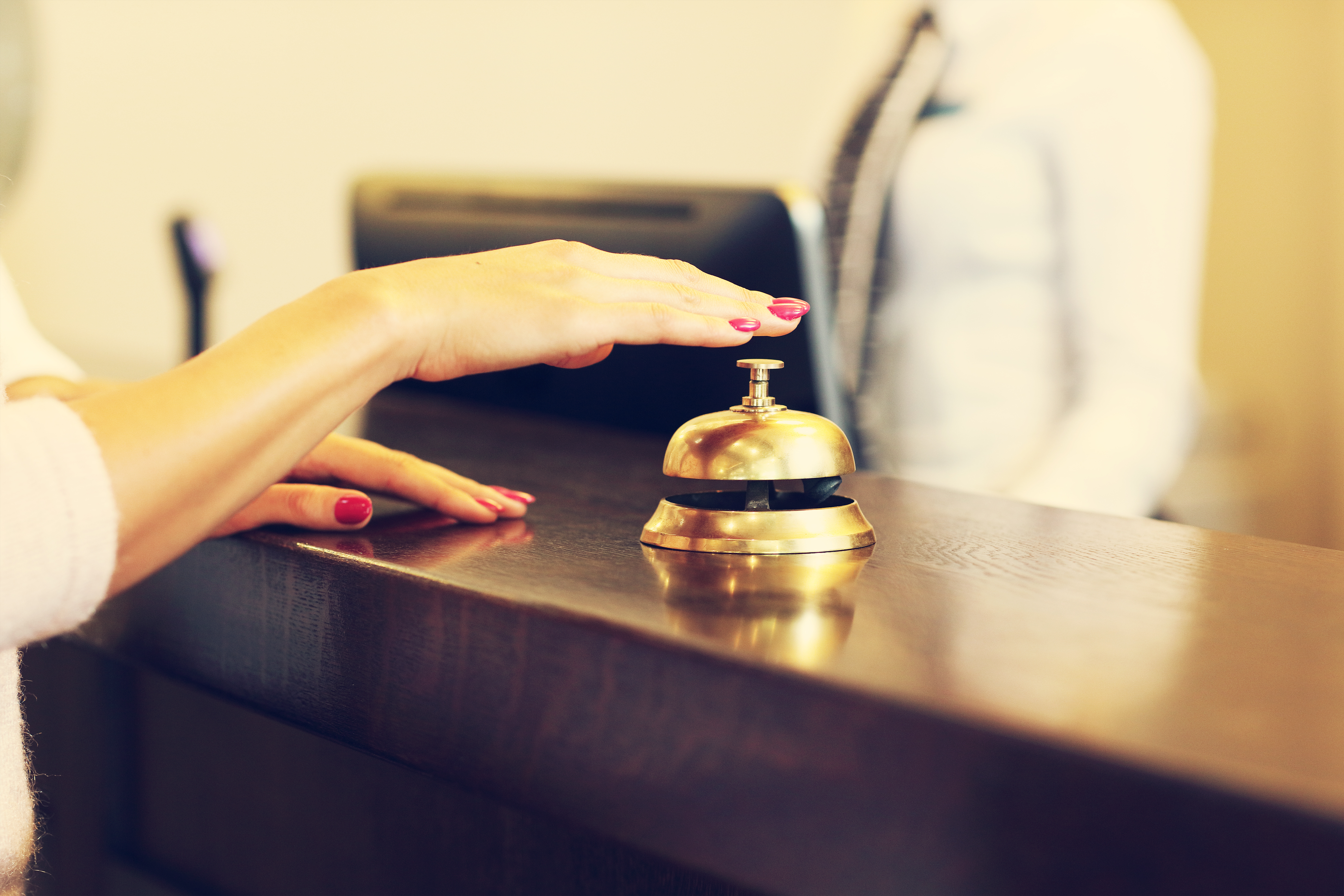 A woman ringing a bell at a hotel reception desk | Source: Shutterstock