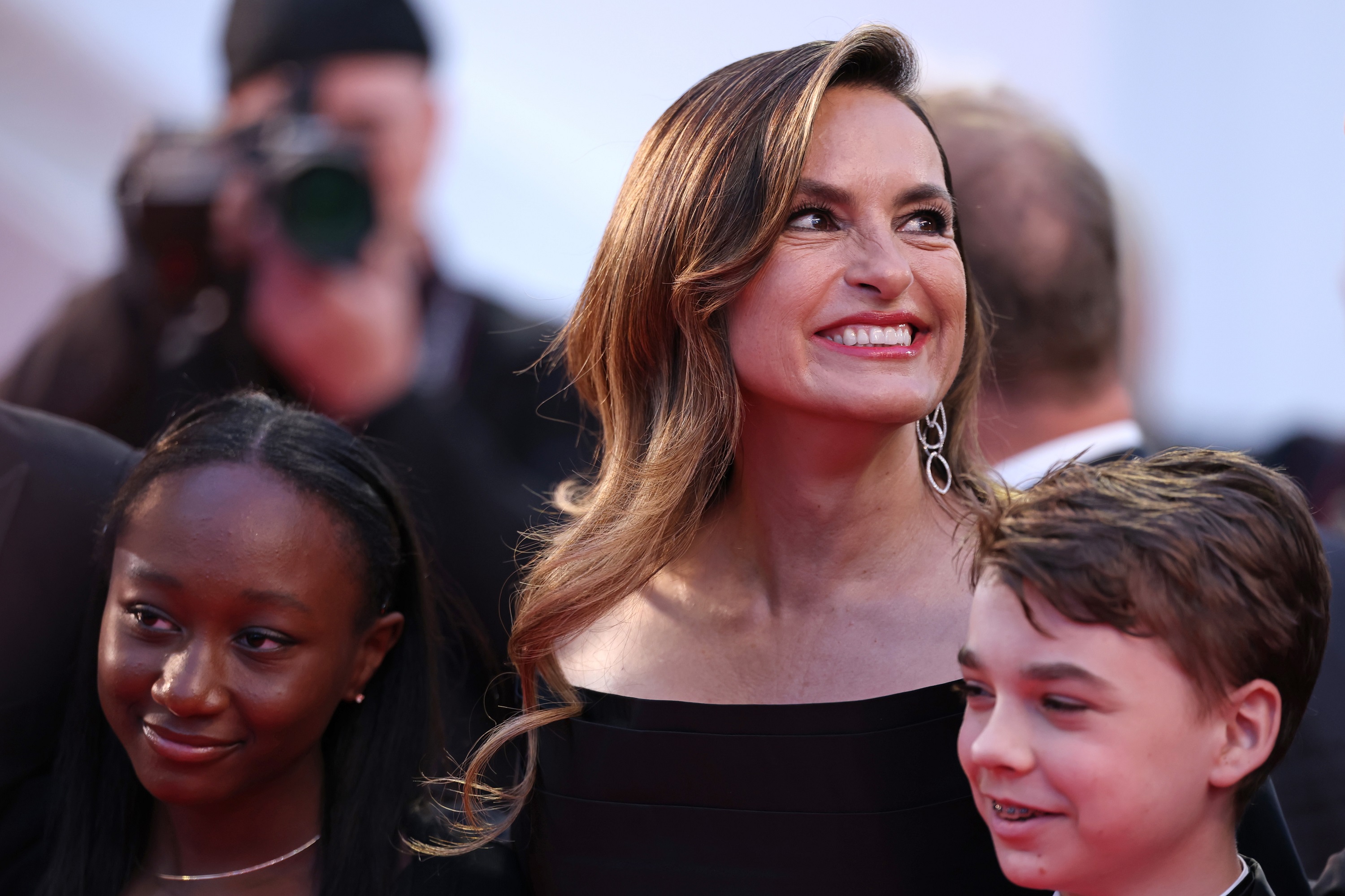 Mariska glows with pride and joy as she smiles brightly, surrounded by Amaya and Andrew. Her radiant expression and warm presence capture a moment of pure happiness on the red carpet.