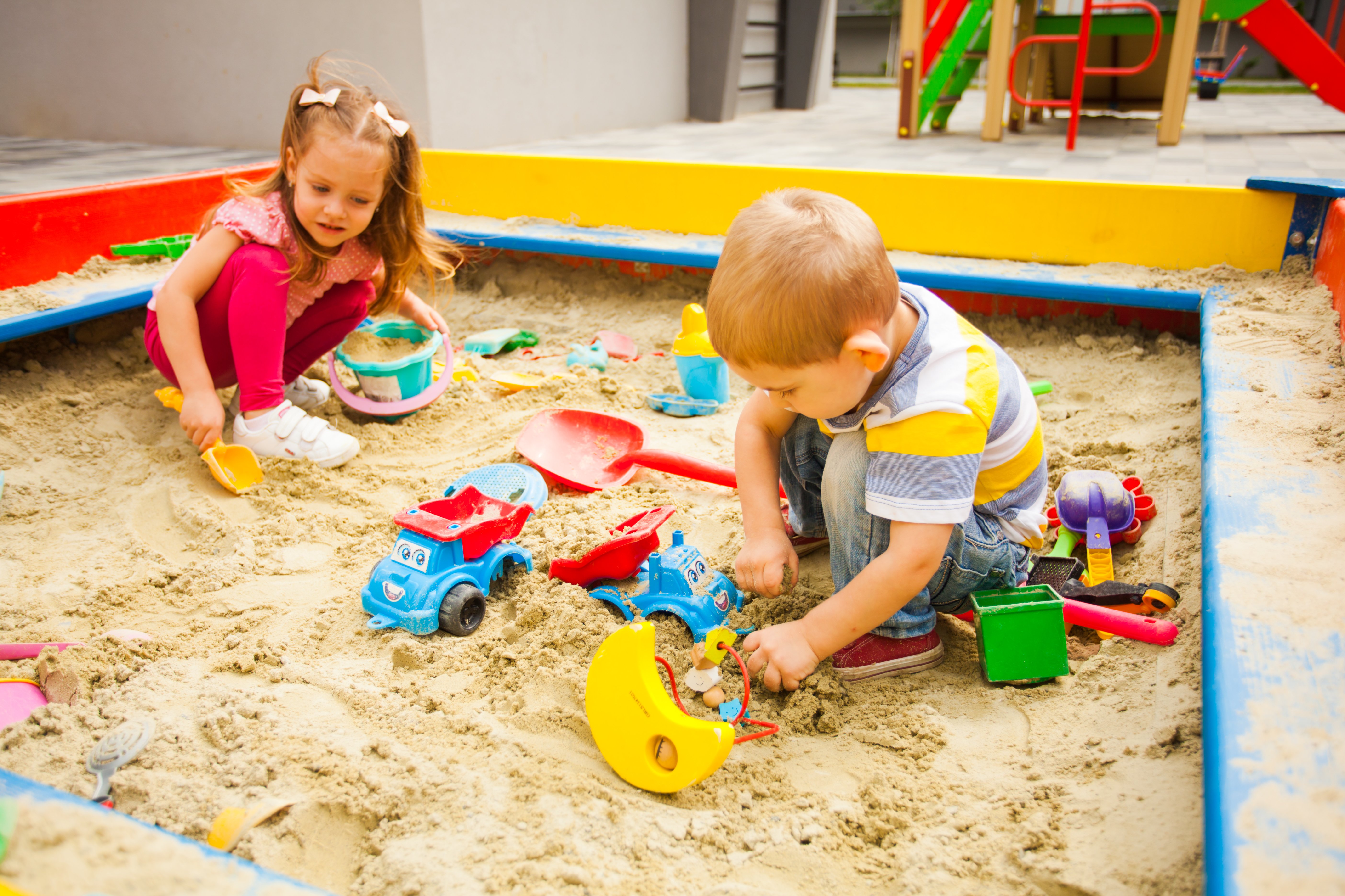 Kleiner Junge und Mädchen spielen mit Sand am modernen Spielplatz | Quelle: Shutterstock