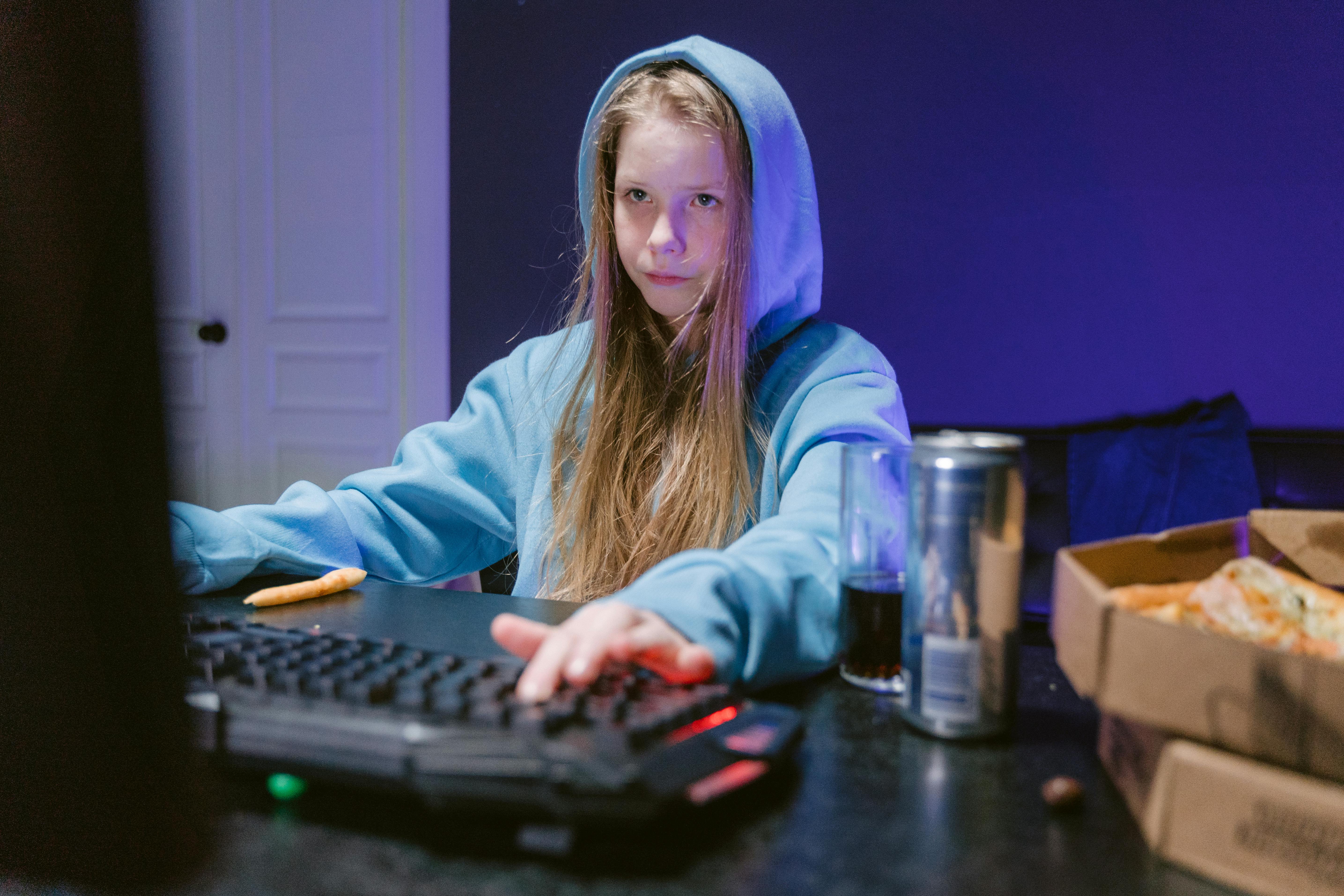 A girl using a computer in her room with beverages and food on hand | Source: Pexels