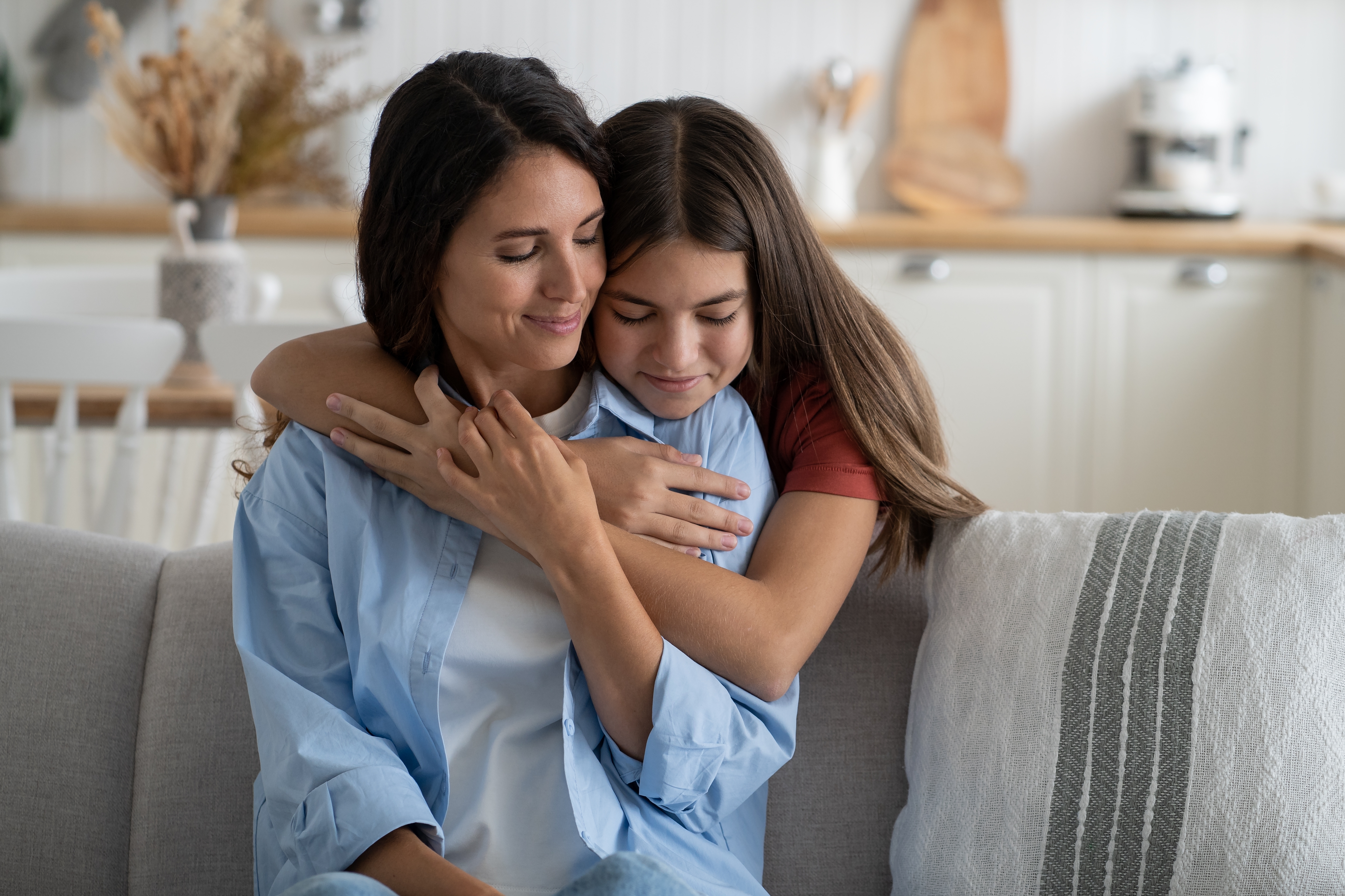 A young girl embracing her mom from behind | Source: Shutterstock