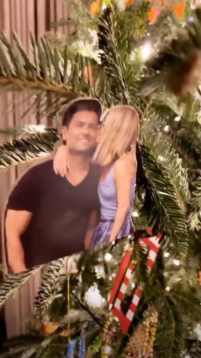 A photo of Kelly Ripa pecking Mark Consuelos hanging on a Christmas tree | Photo: Instagram/Kelly Ripa