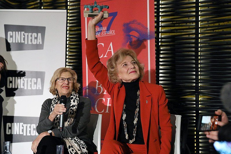Marisa Paredes y la alcaldesa de Madrid, Manuel Carmena, en los premios “Puerta de Toledo” en el marco de la 37ª Semana de Cine Español en Carabanchel, 17 de enero de 2019. | Imagen: Wikimedia Commons Marisa Paredes y la alcaldesa de Madrid, Manuel Carmena, en los premios “Puerta de Toledo” en el marco de la 37ª Semana de Cine Español en Carabanchel, 17 de enero de 2019. | Imagen: Wikimedia Commons