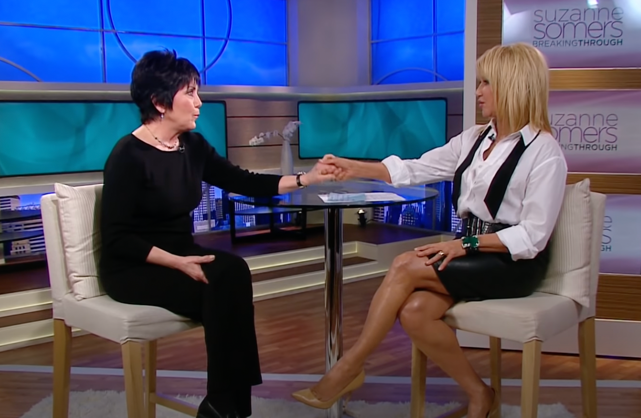 Joyce DeWitt and Suzanne Somers hold hands during an interview on "Suzanne Somers: Breaking Through" on February 2, 2012 | Source: YouTube/CafeMomsStudio