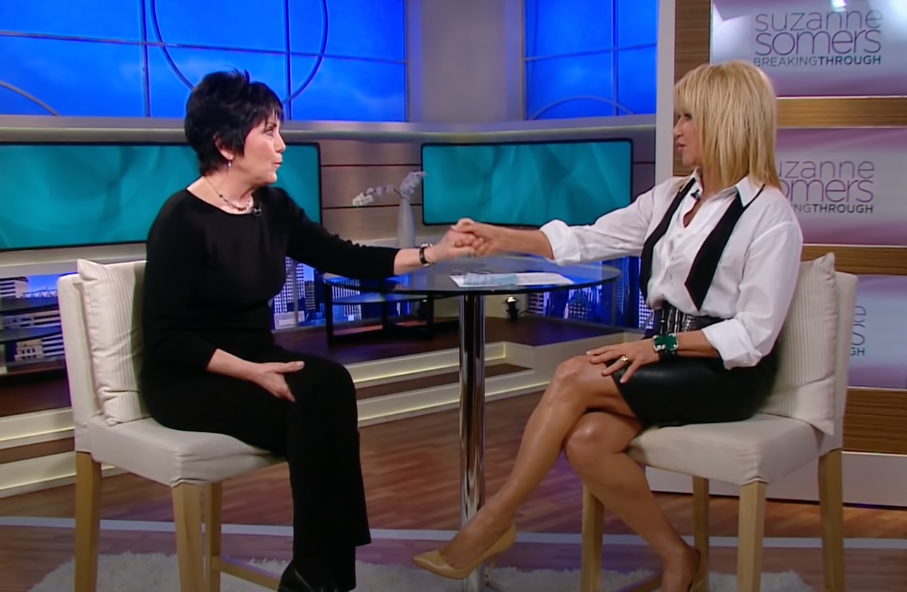 Joyce DeWitt and Suzanne Somers hold hands during an interview on "Suzanne Somers: Breaking Through" on February 2, 2012 | Source: YouTube/@CafeMomsStudio