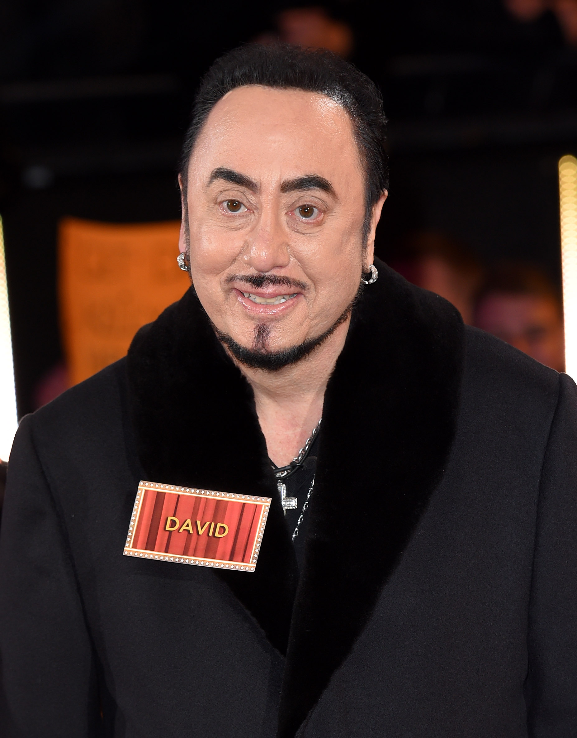 David Gest smiled for the cameras as he entered the "Celebrity Big Brother" house at Elstree Studios in Borehamwood, England, on January 5, 2016. Dressed in a black coat with a plush collar and wearing silver hoop earrings, Gest joined the reality series only months before his death, marking one of his final appearances in the British television spotlight.