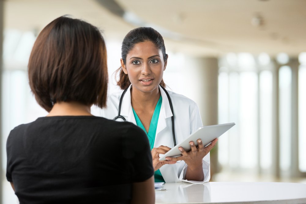 A doctor talking with female patient in doctors office. | Photo: Shutterstock