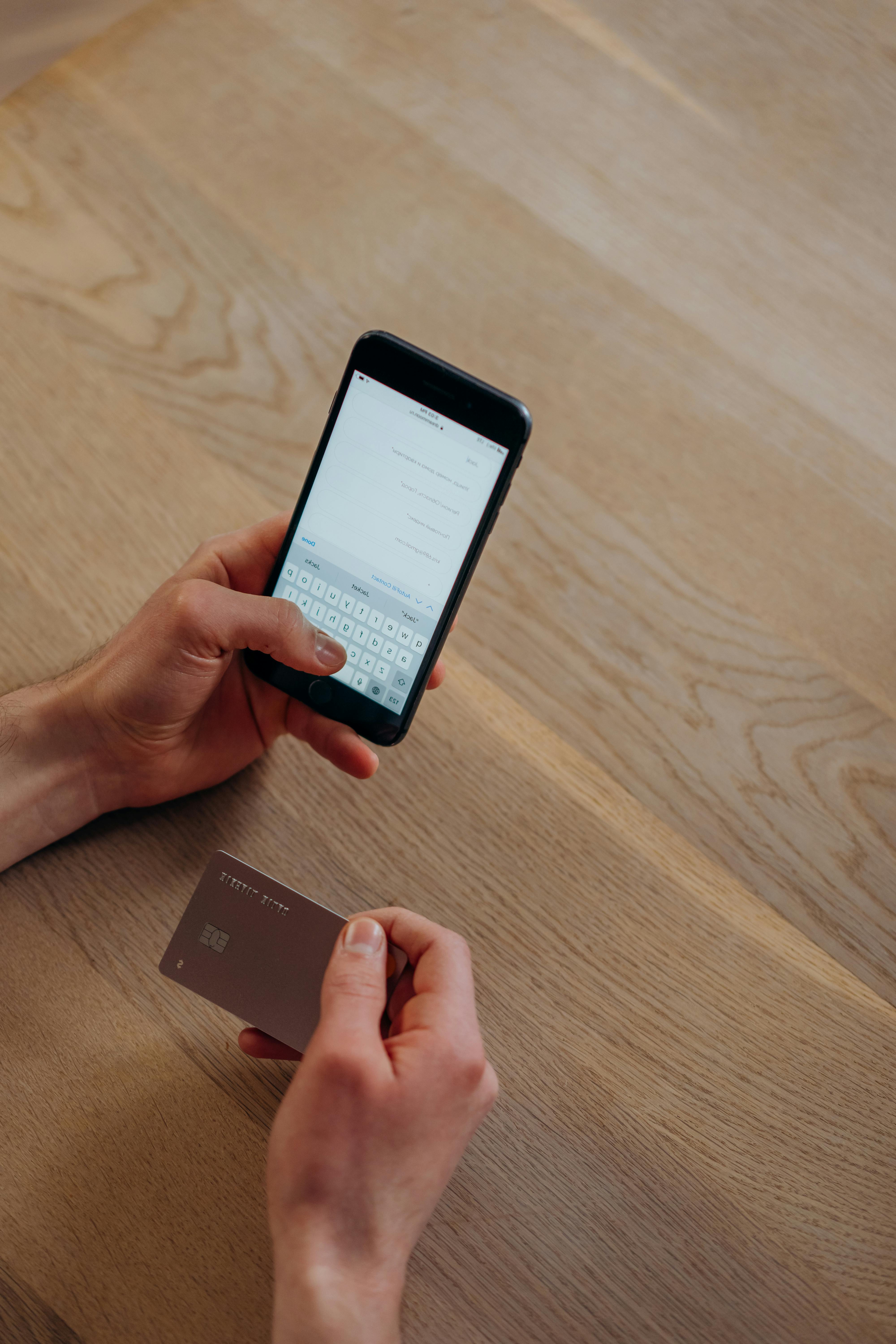 A person texting while holding a credit card | Source: Pexels