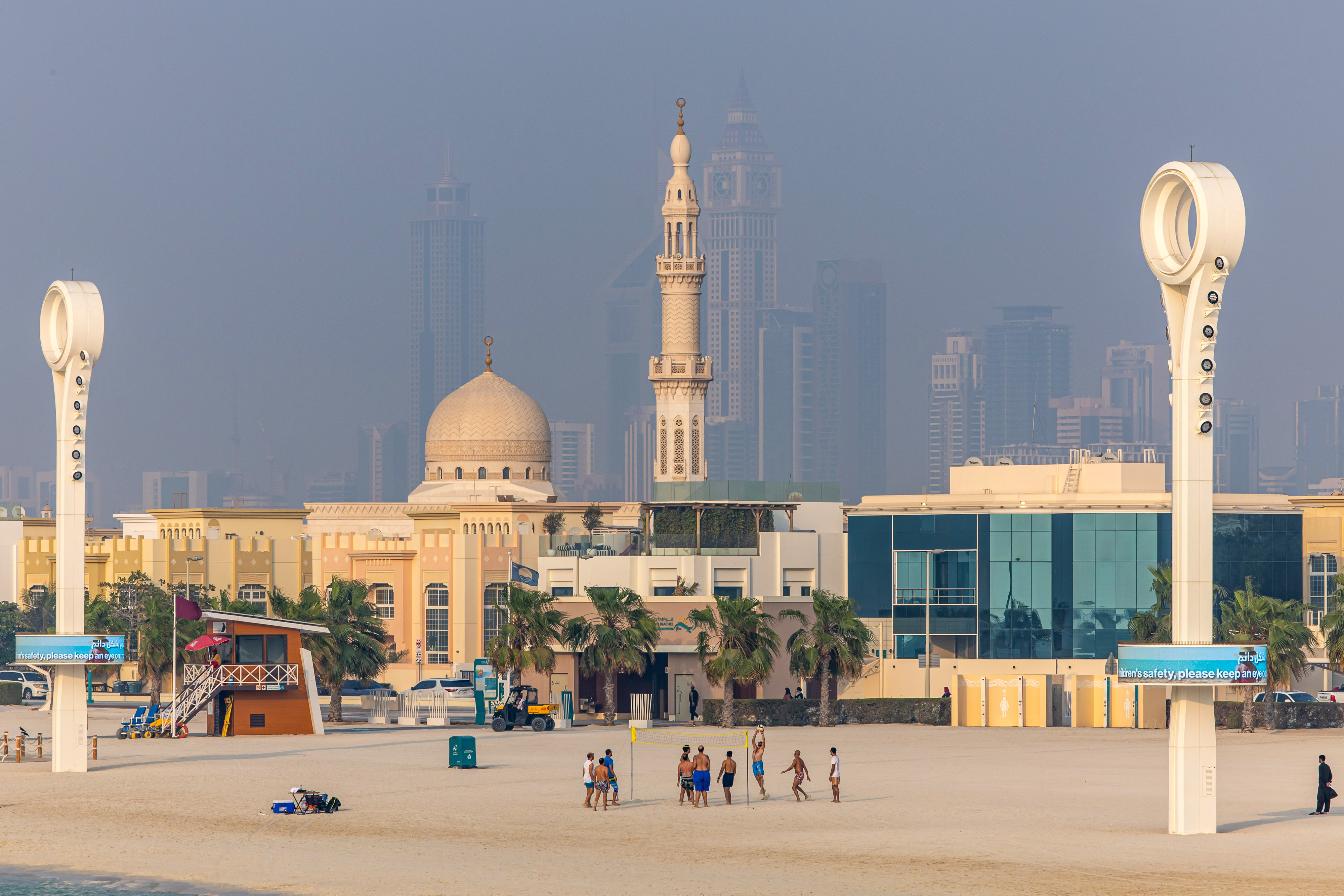 Beachgoers play volleyball, backdropped by residential and commercial properties in the Jumeirah Beach district of Dubai, United Arab Emirates, on August 25, 2023 | Source: Getty Images