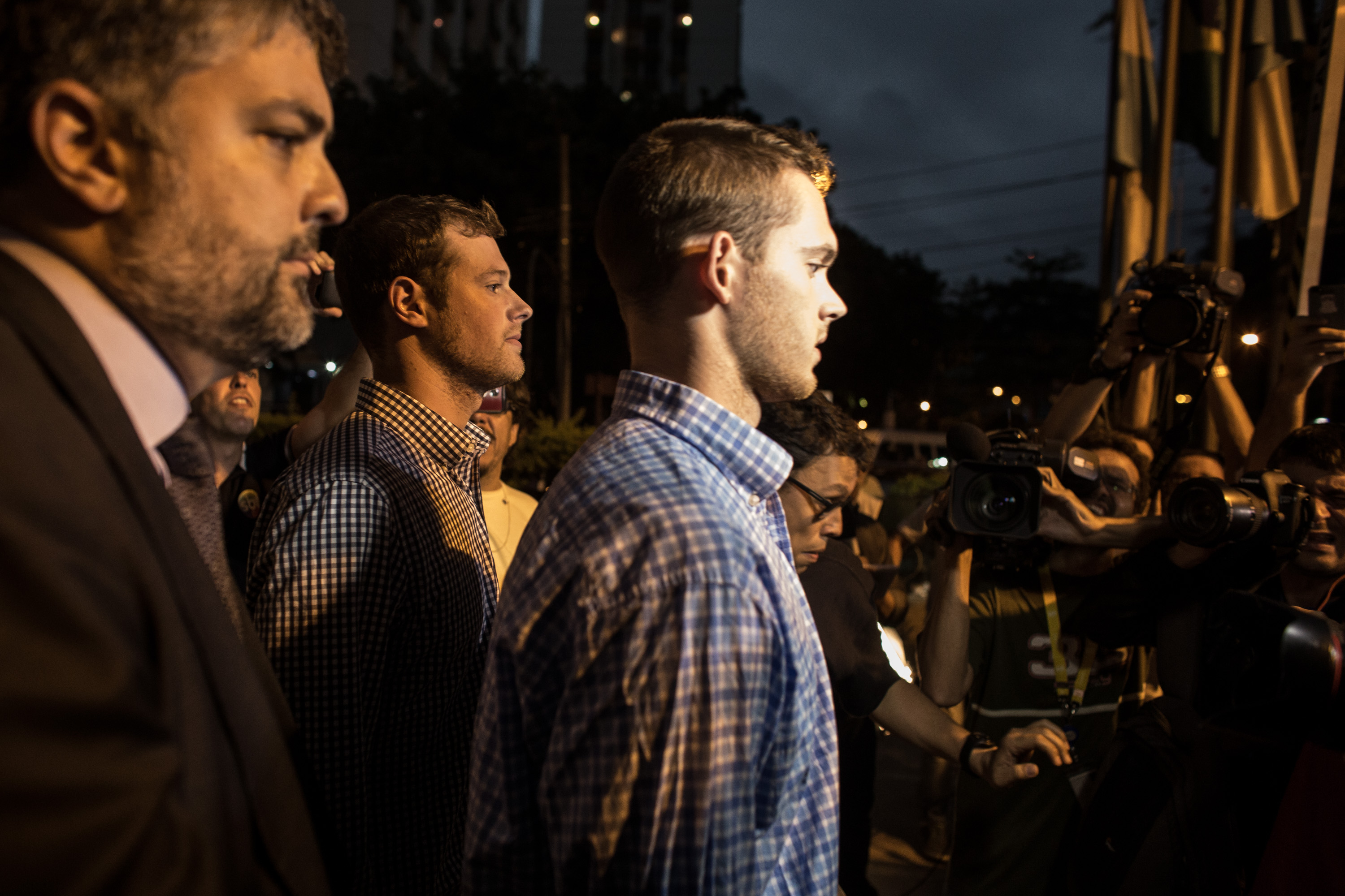 Gunnar Bentz and Jack Conger are mobbed by the media and onlookers while leaving the police station after questioning in Rio de Janiero, Brazil, on August 18, 2016. | Source: Getty Images