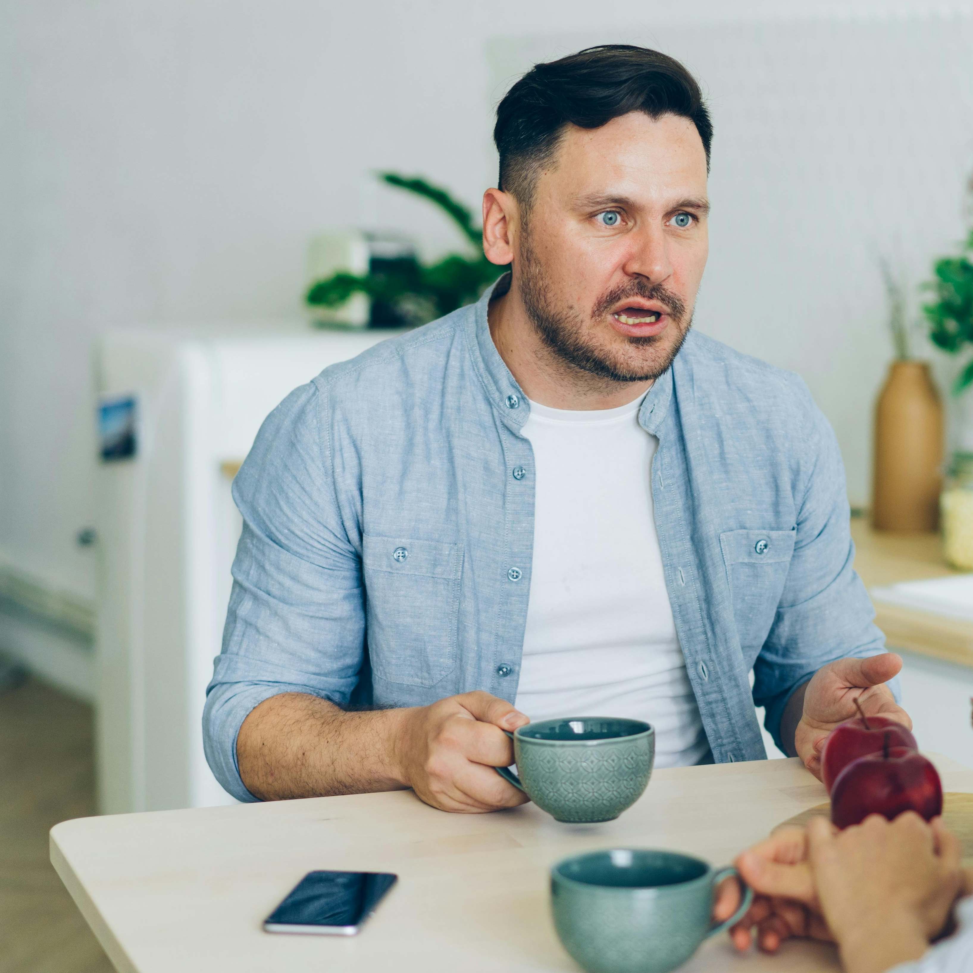 A man sitting across a table from someone, reacting with surprise | Source: Pexels