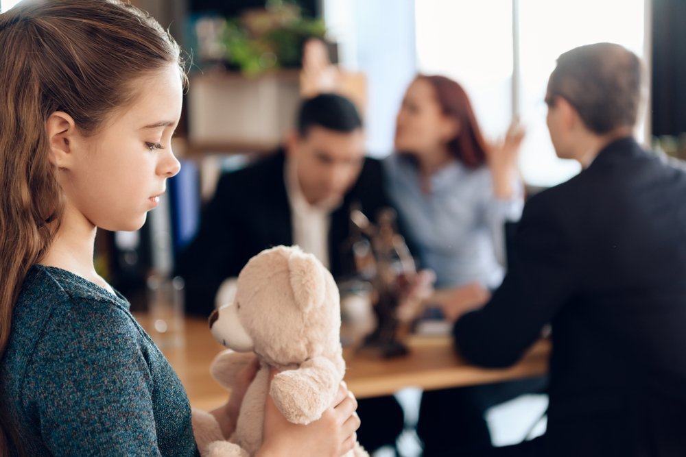 Erwachsene streiten im Raum, während das Kind traurig auf den Teddy schaut | Quelle: Shutterstock