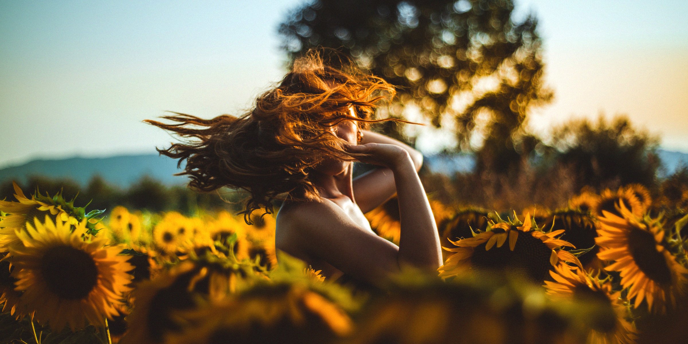 Unsplash | A woman dancing in a field of sunflowers