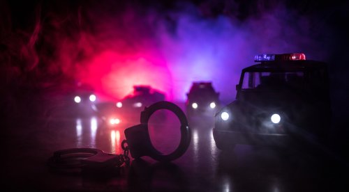 Silhouette von Handschellen mit Polizeiwagen auf der Rückseite | Quelle: Shutterstock