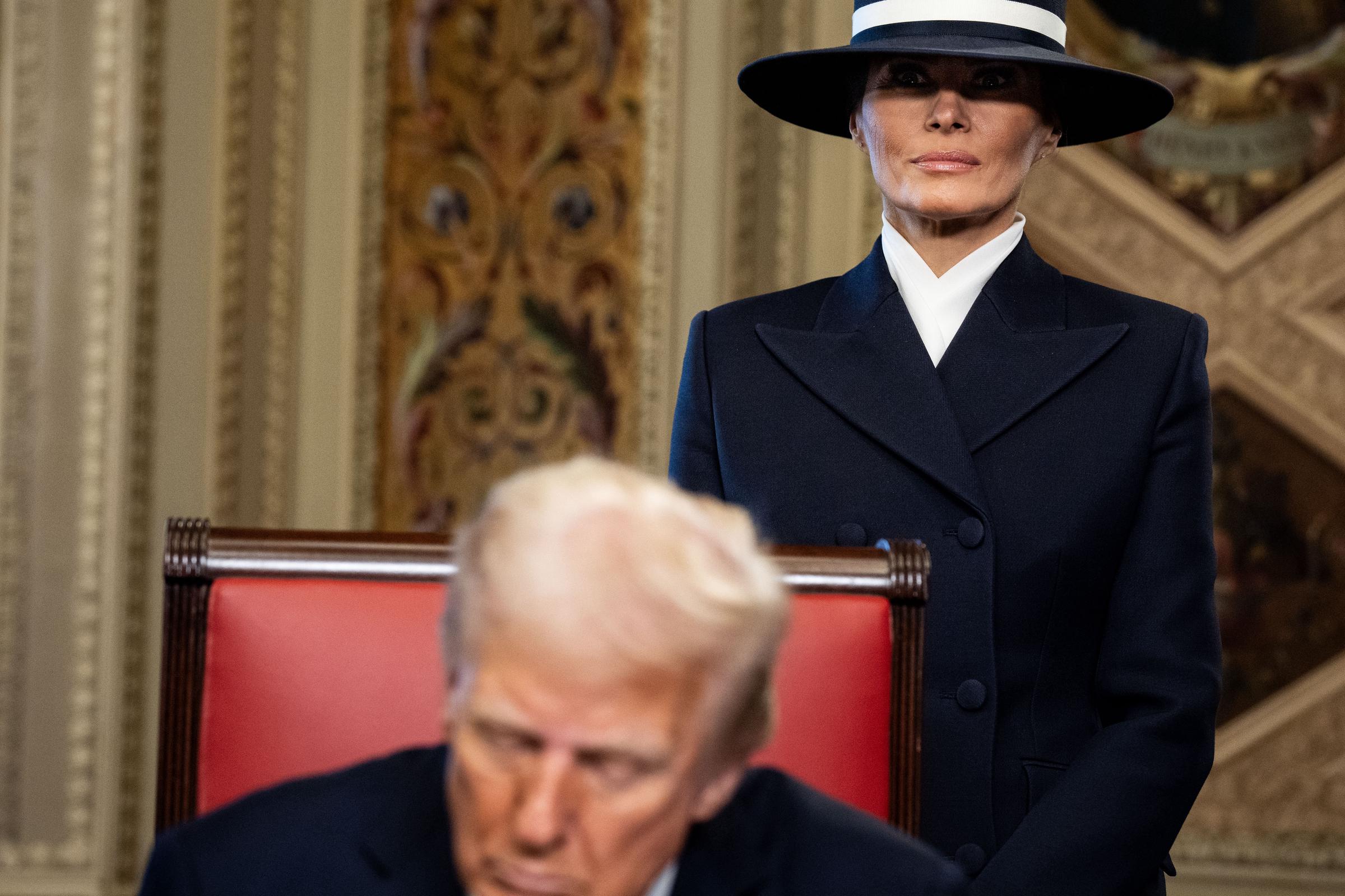 President Donald Trump signing official documents in the President's Room with First Lady Melania Trump in the background on January 20, 2025, at the US Capitol in Washington, D.C. | Source: Getty Images