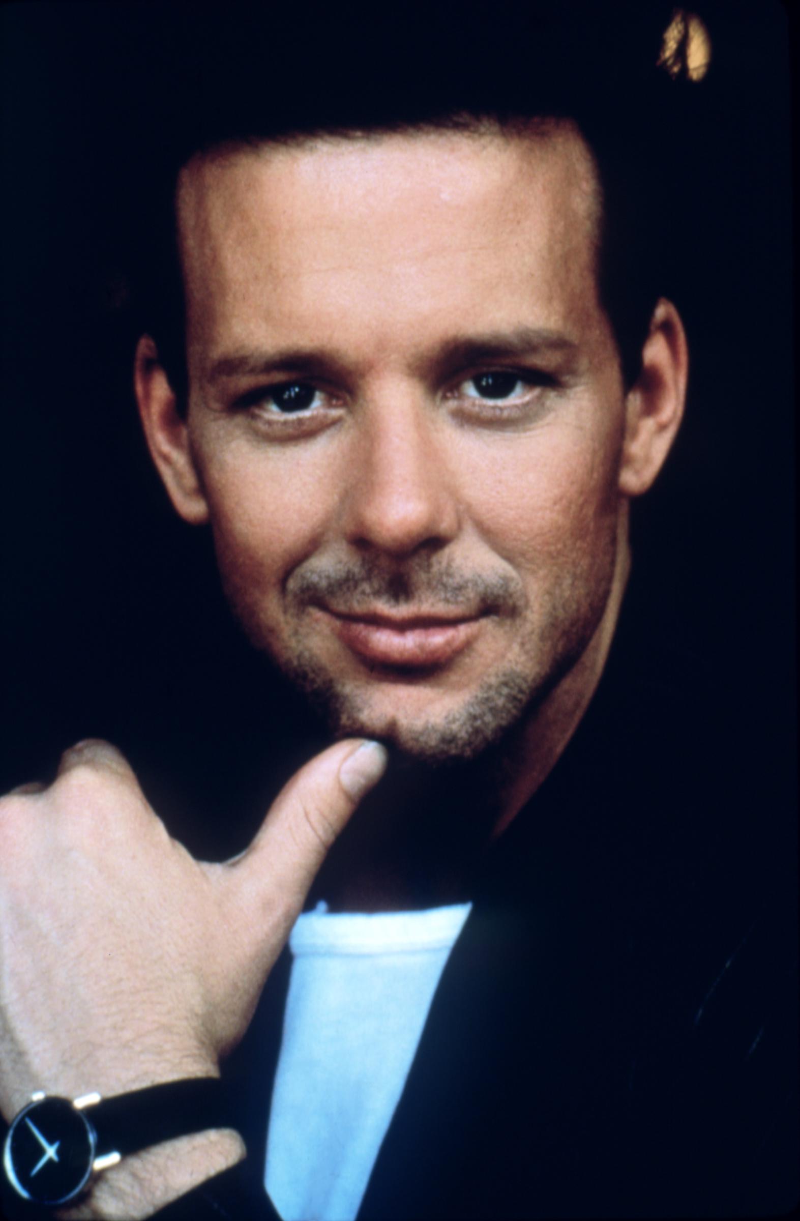 By 1986, Mickey Rourke's heartthrob era was in full swing, and this close-up from the set of "Nine 1/2 Weeks" captured the actor with neatly styled dark hair, light stubble, and his hand resting beneath his chin. The romantic drama became one of his defining films of the decade, pairing him with Kim Basinger and further cementing the leading-man image he had built throughout the 1980s.