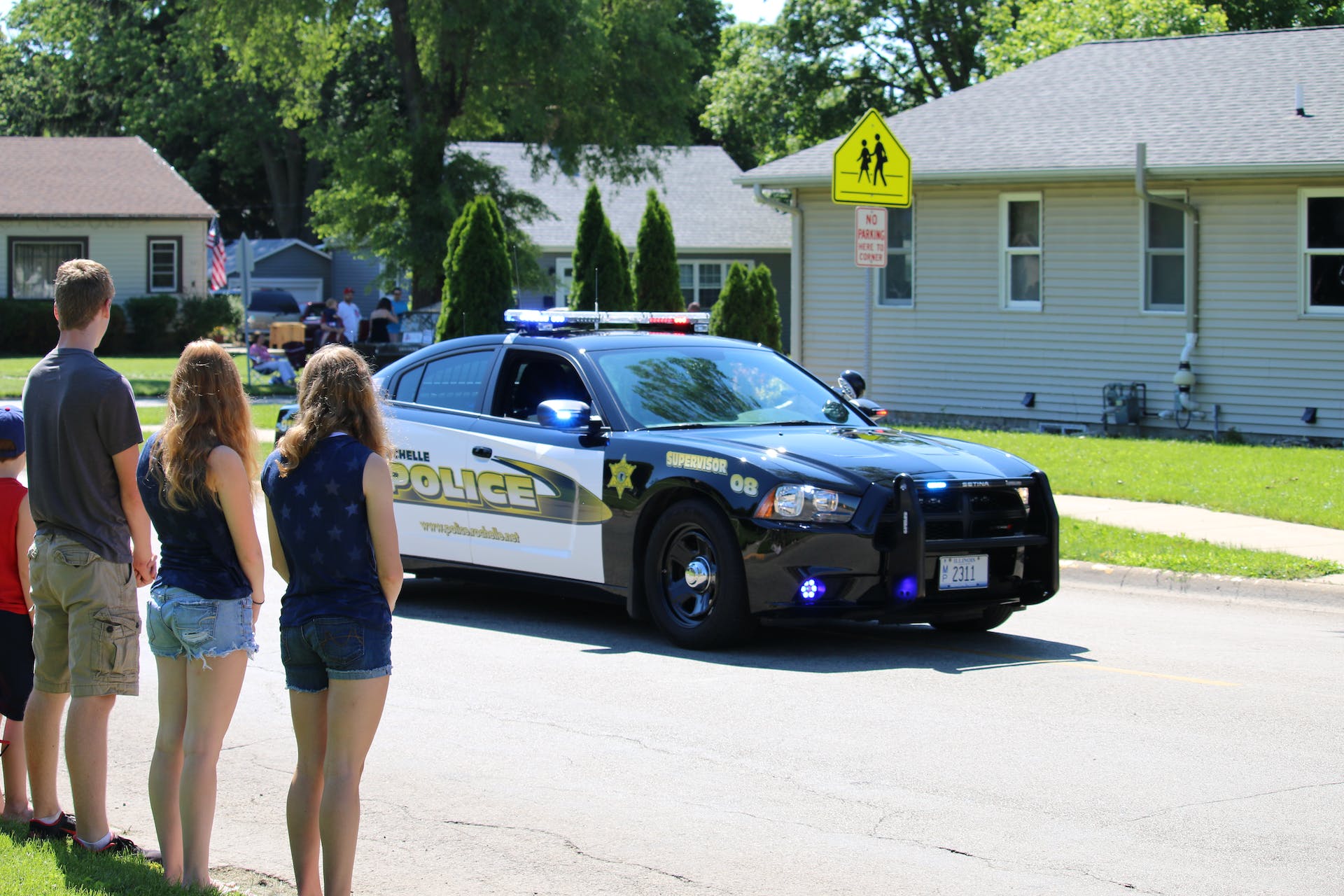 People looking at a police car passing through a neighborhood | Source: Pexels