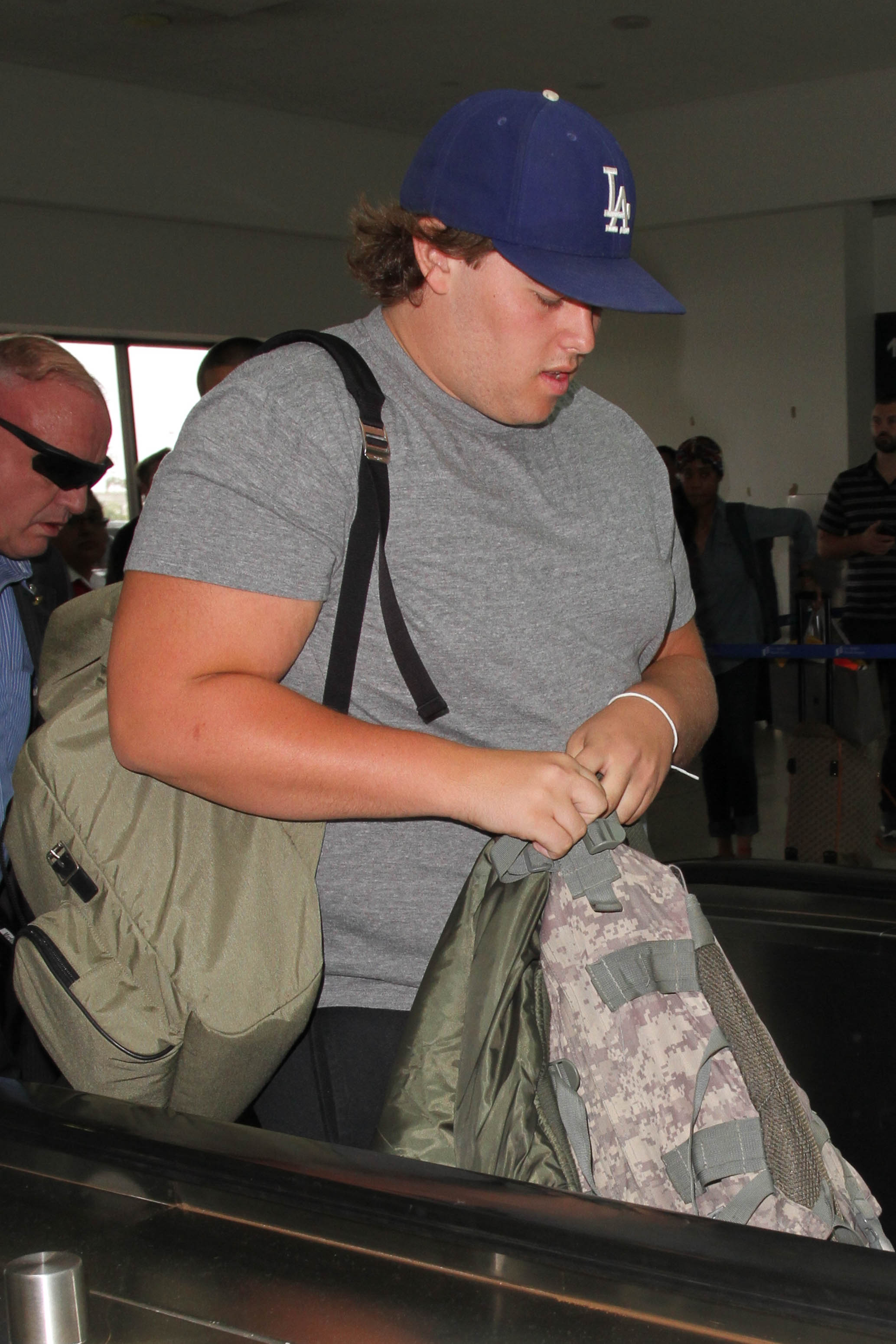 In another shot from the same day, Christopher walks outside the terminal in casual athletic wear, including black shorts and gray sneakers. His cap and loose hairstyle add to the laid-back look as he moves with a purposeful stride.